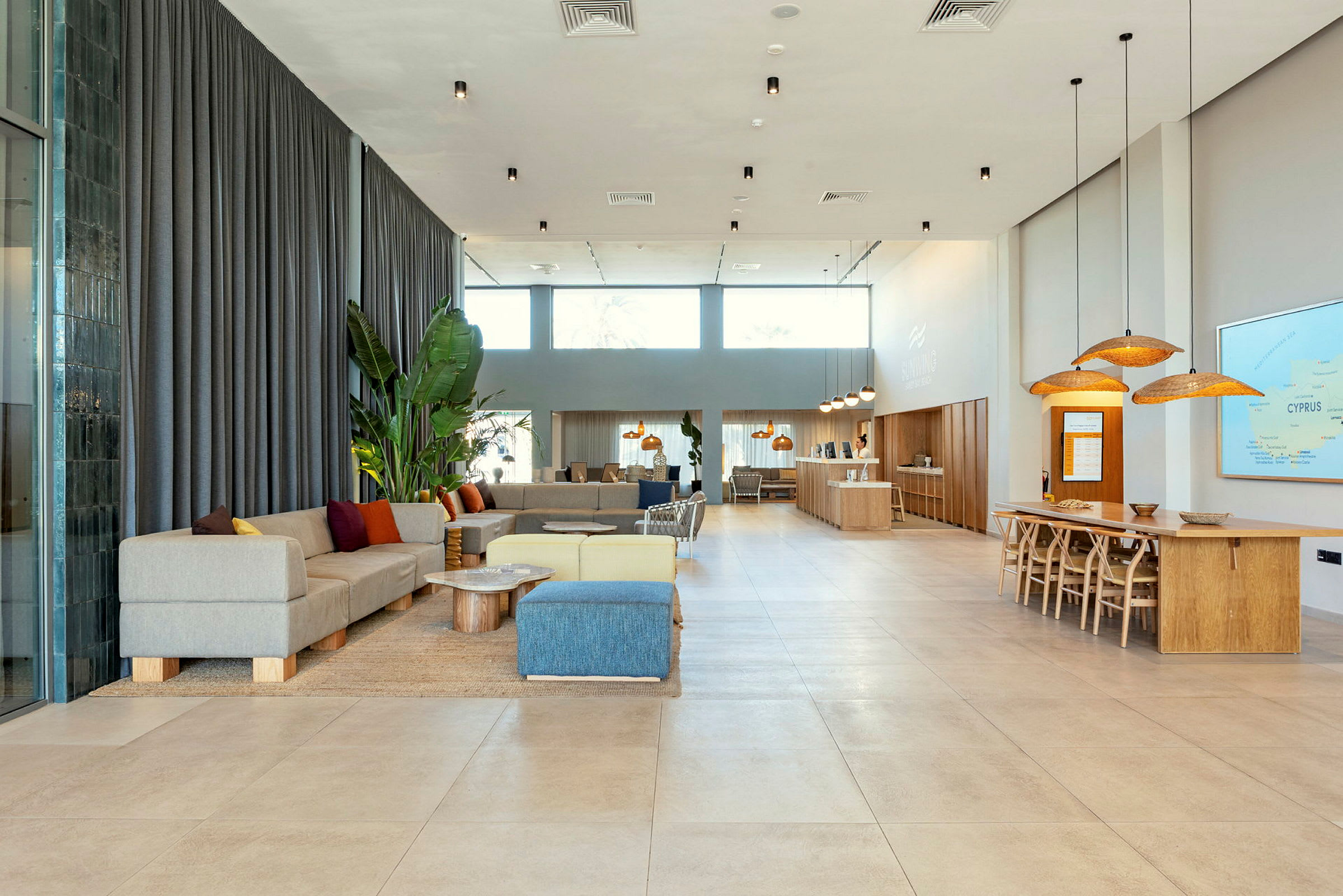 Ett modernt och ljust inrett hotellobbyområde med sittplatser, bord och en reception. (AI-genererad text)
