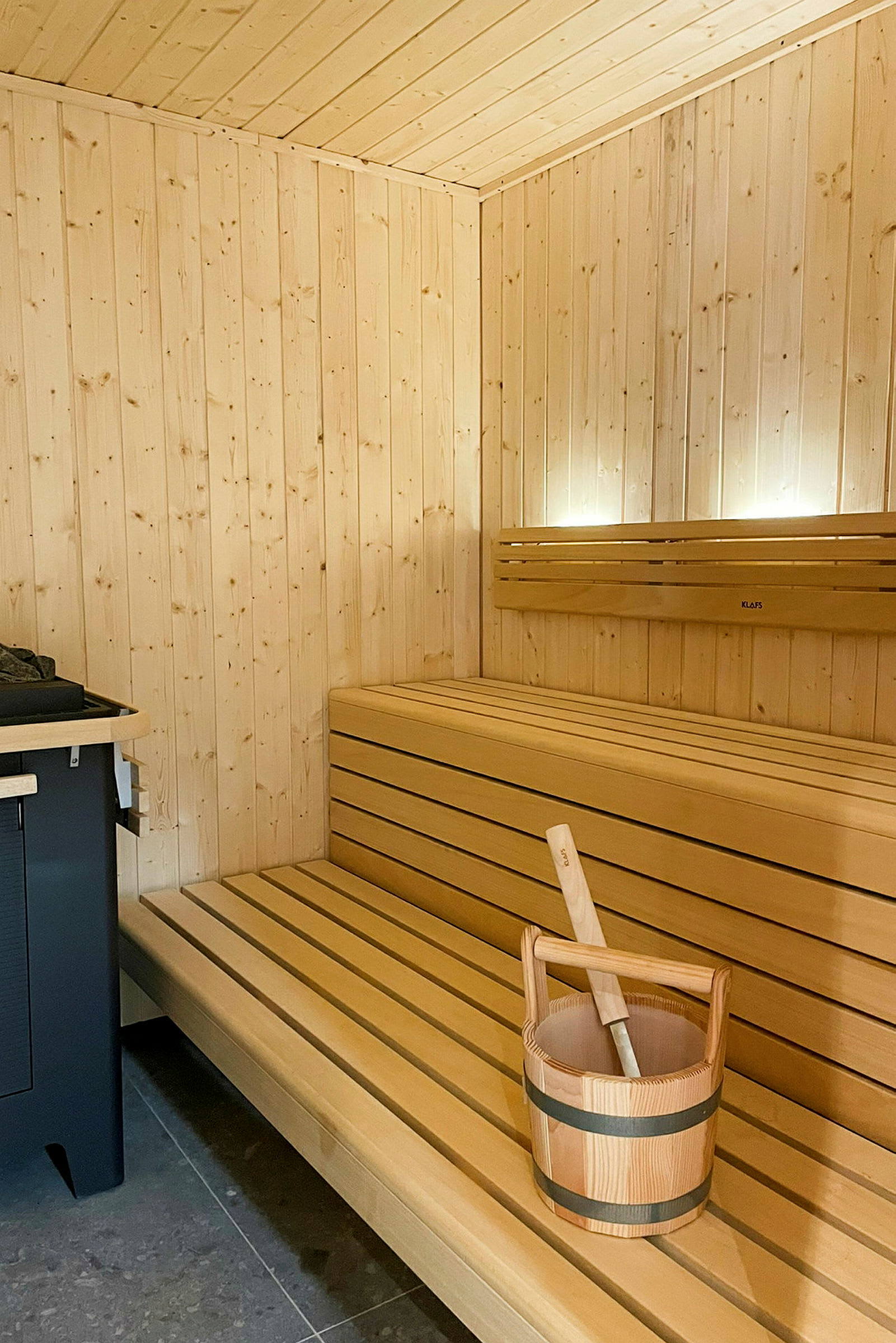 En bastu med träpaneler, en träbänk och en hink med slev i för ånga. (AI-genererad text)