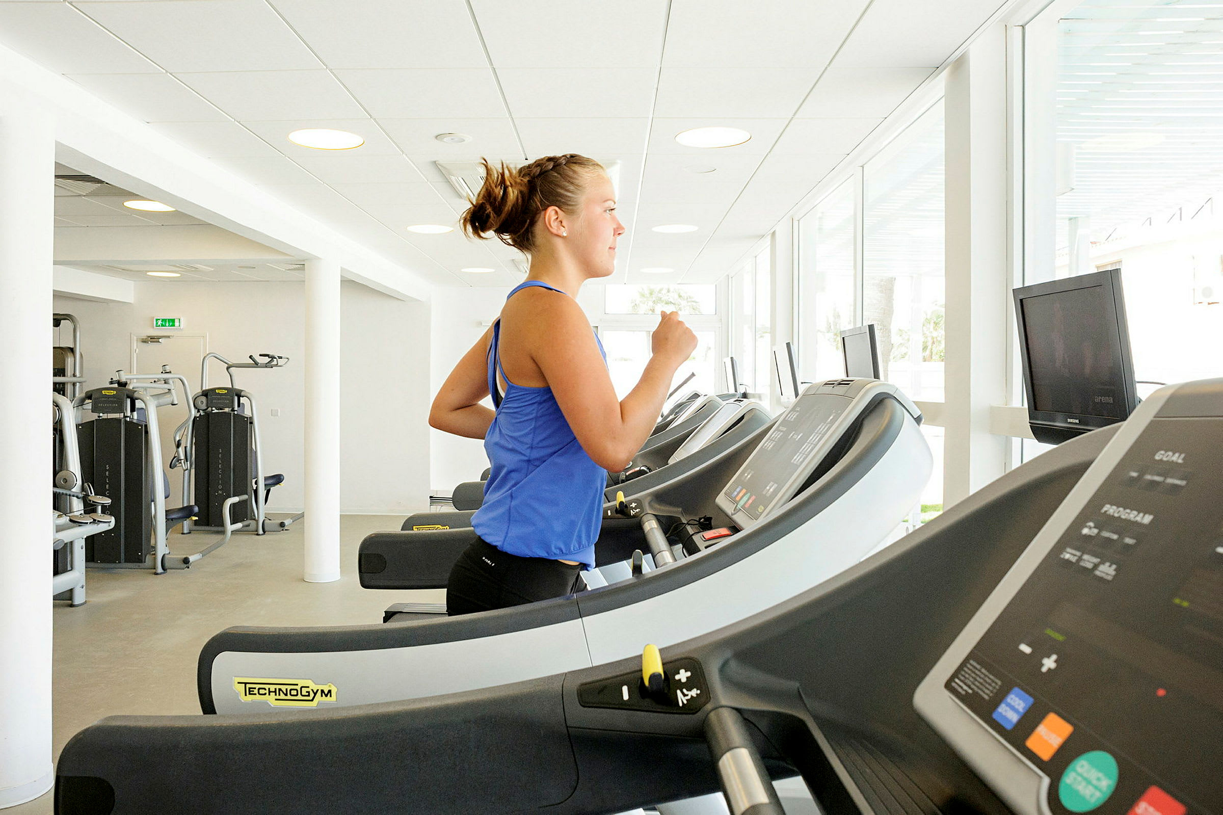 En person tränar på ett löpband i ett ljust gym. (AI-genererad text)