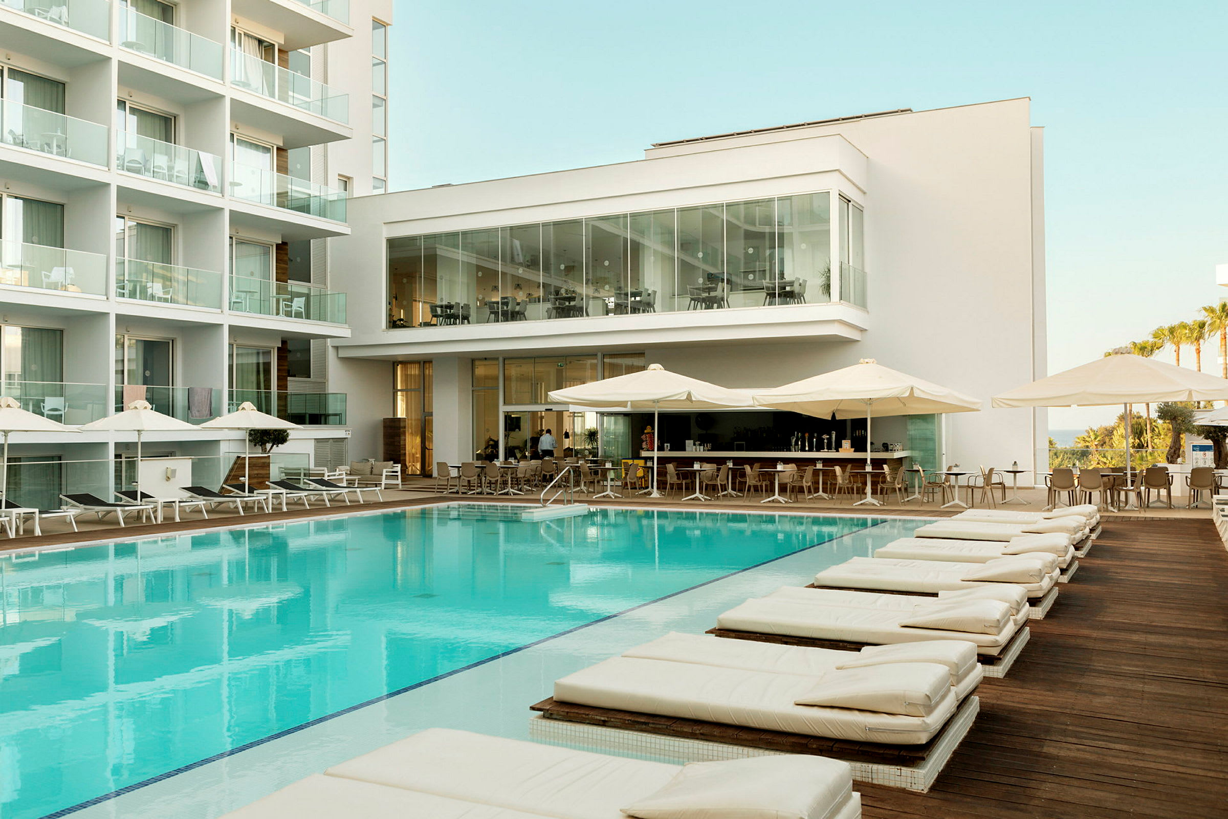 Bild av ett hotellområde med pool, solstolar och en utomhusbar. (AI-genererad text)