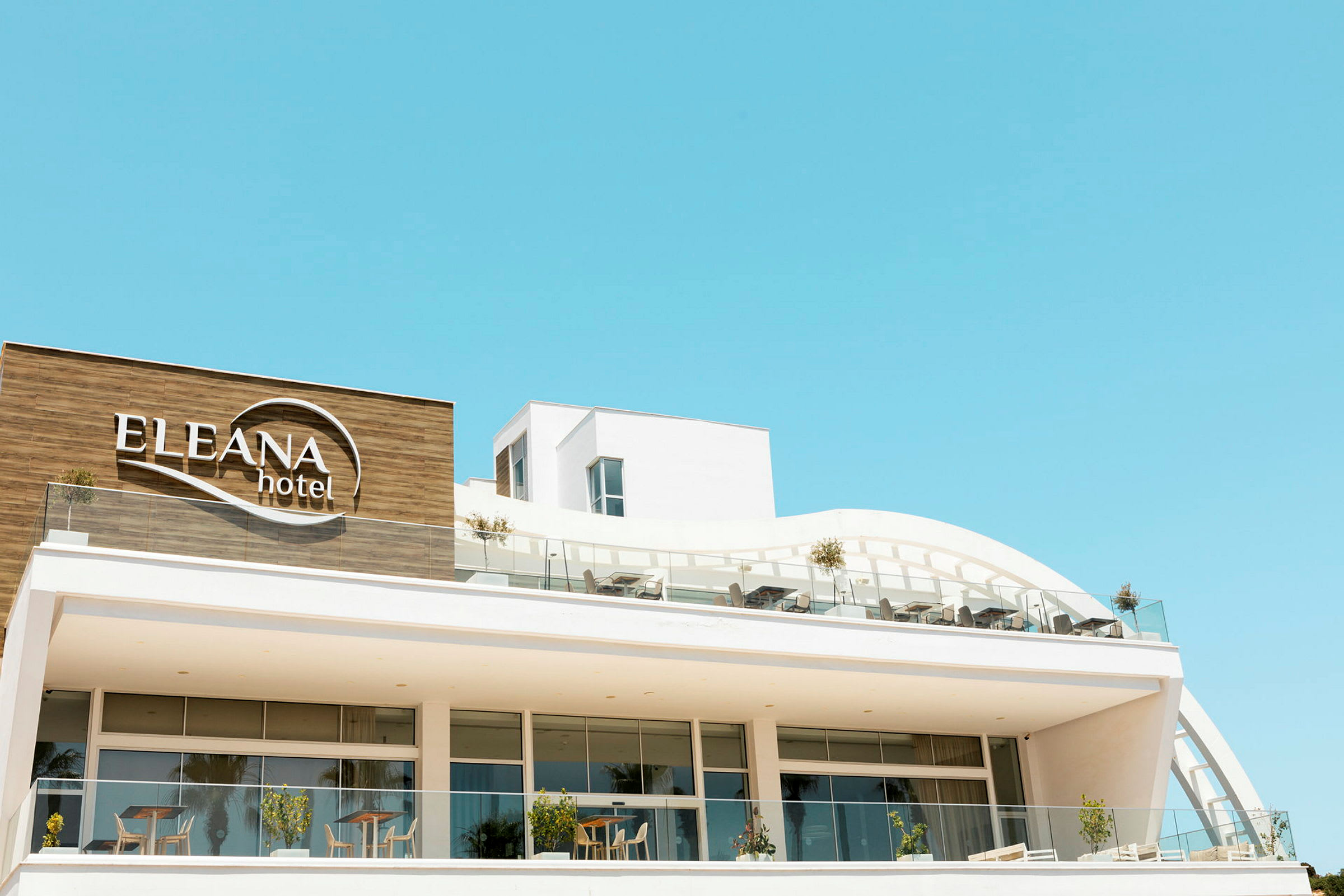 Modernt hotell med namnet Eleana Hotel synligt på fasaden. (AI-genererad text)