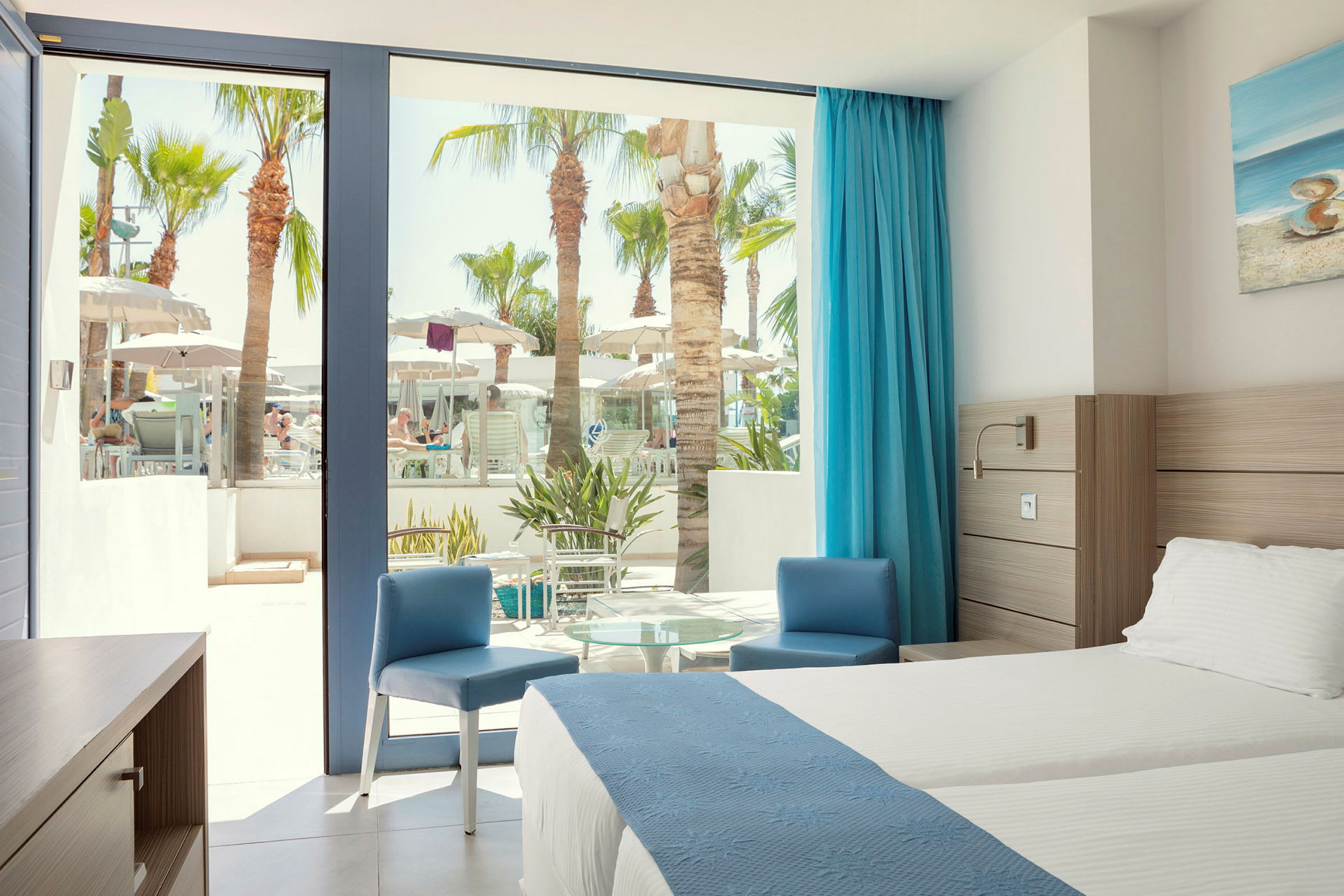Hotellrum med utsikt över poolområde genom stora fönster. (AI-genererad text)