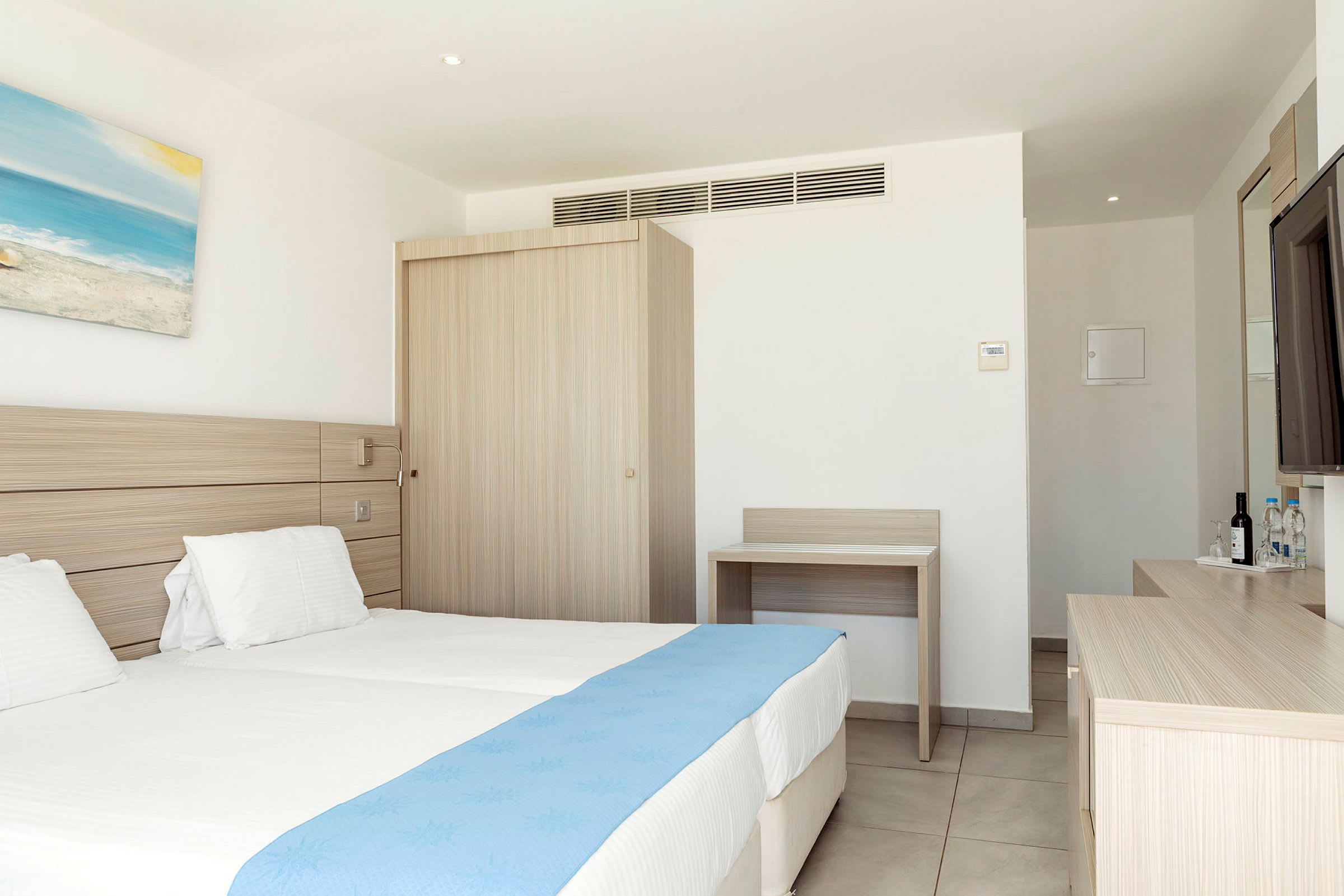 Ett hotellrum med två enkelsängar och en blå sängduk. (AI-genererad text)