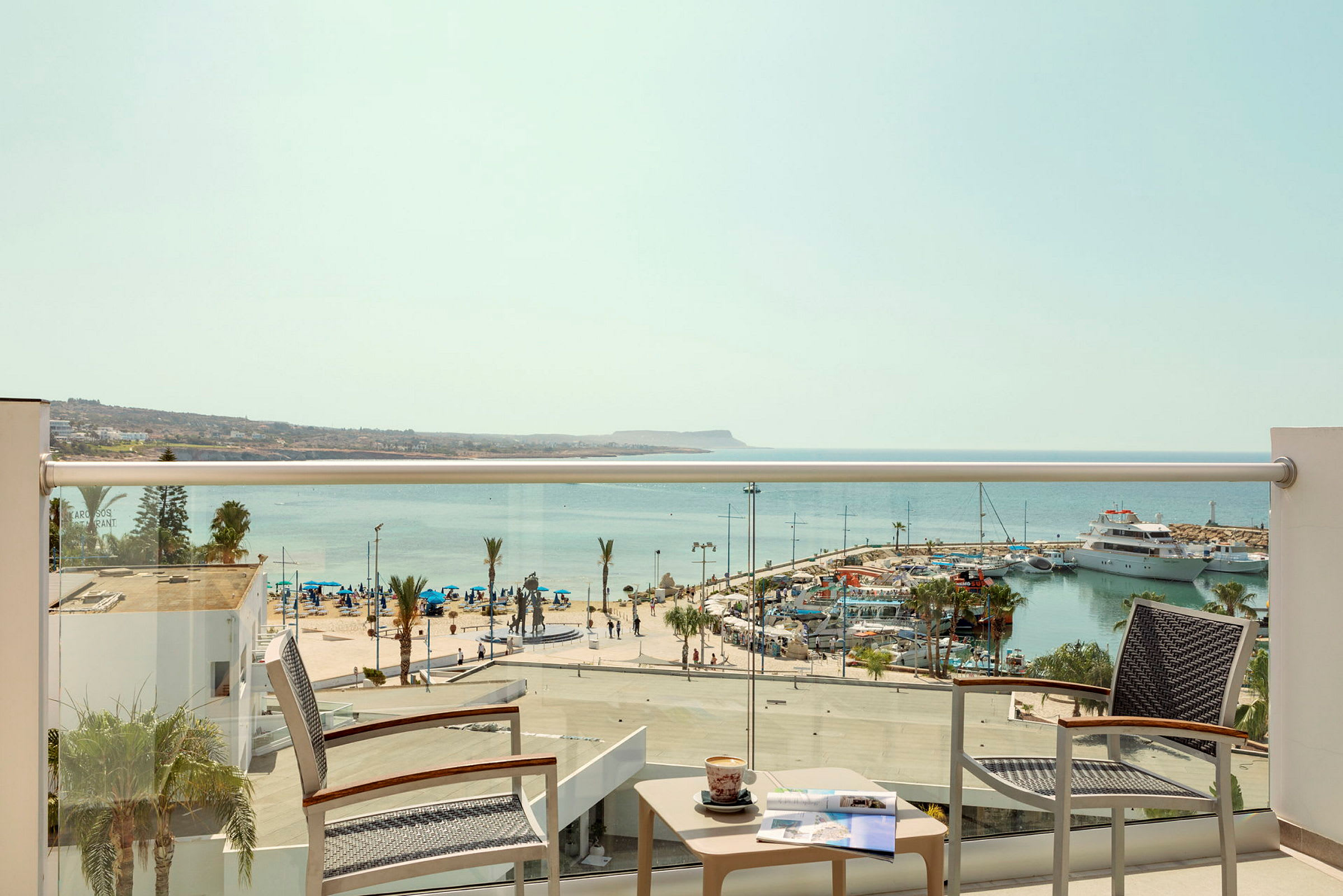Utsikt från en hotellbalkong över en marina och havet. (AI-genererad text)