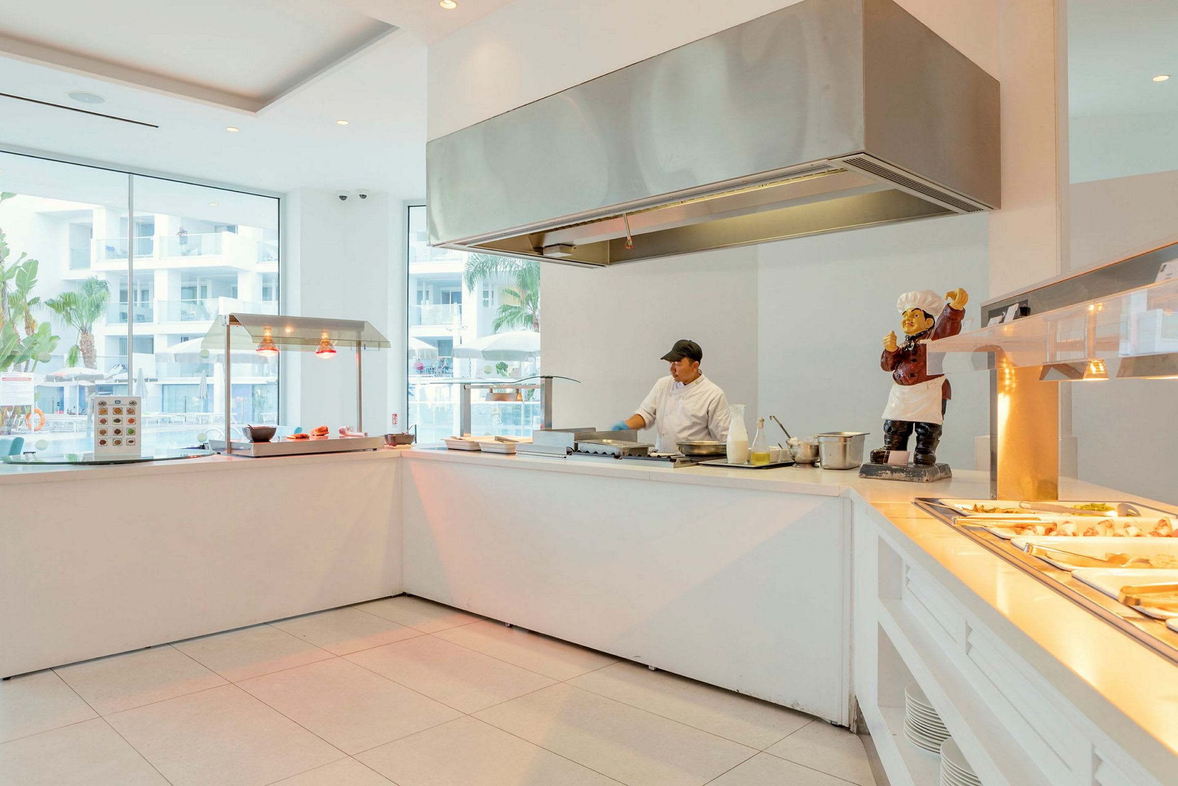 Ett modernt hotellkök med olika matstationer vid stora glasfönster. (AI-genererad text)