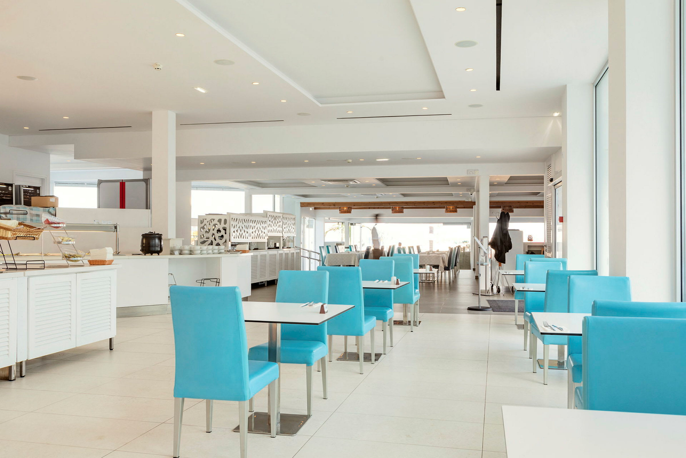 Bild av en modern restaurang med blåa stolar och vit inredning. (AI-genererad text)