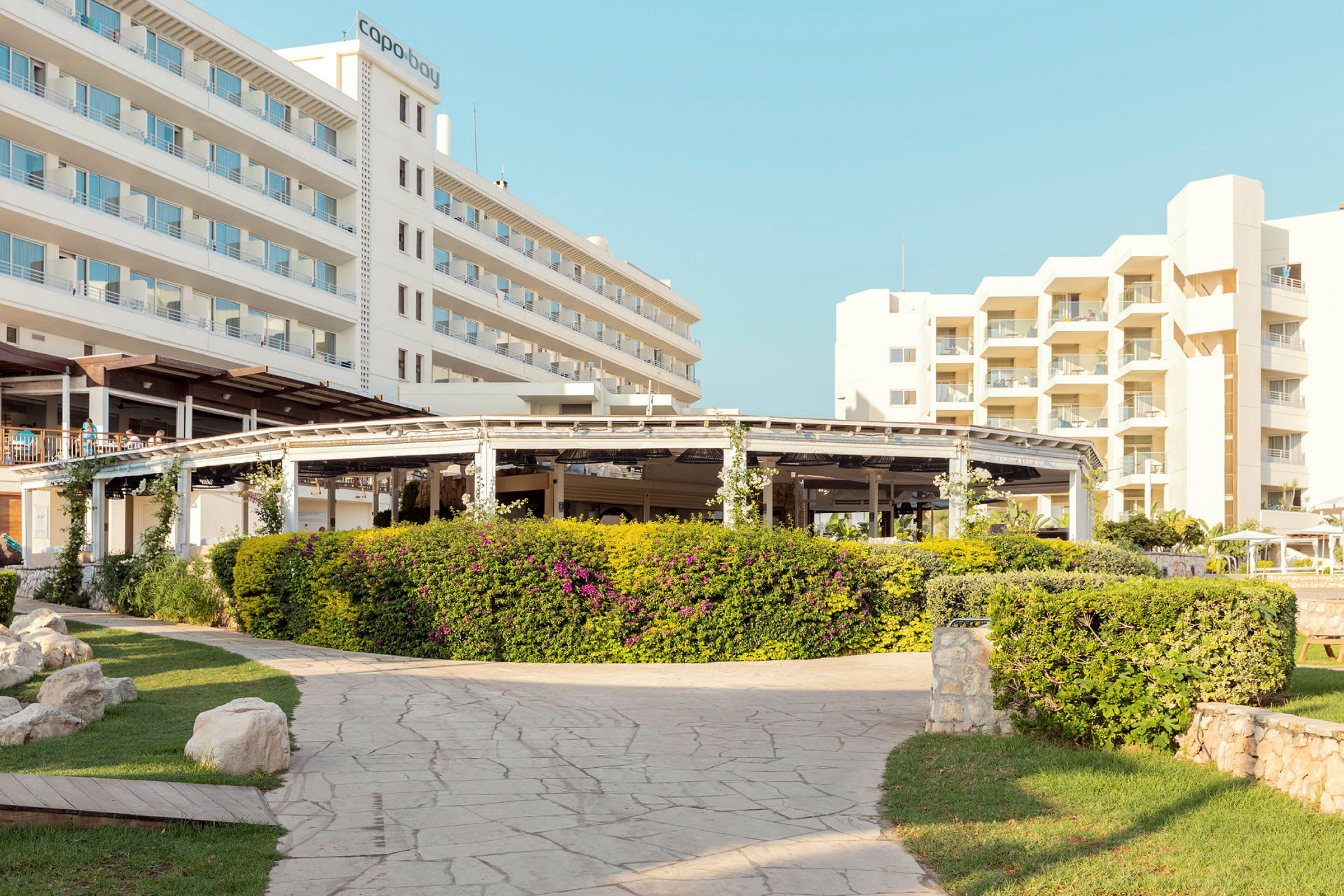 Hotellbyggnader med anslutande gångväg och grönskande trädgård. (AI-genererad text)