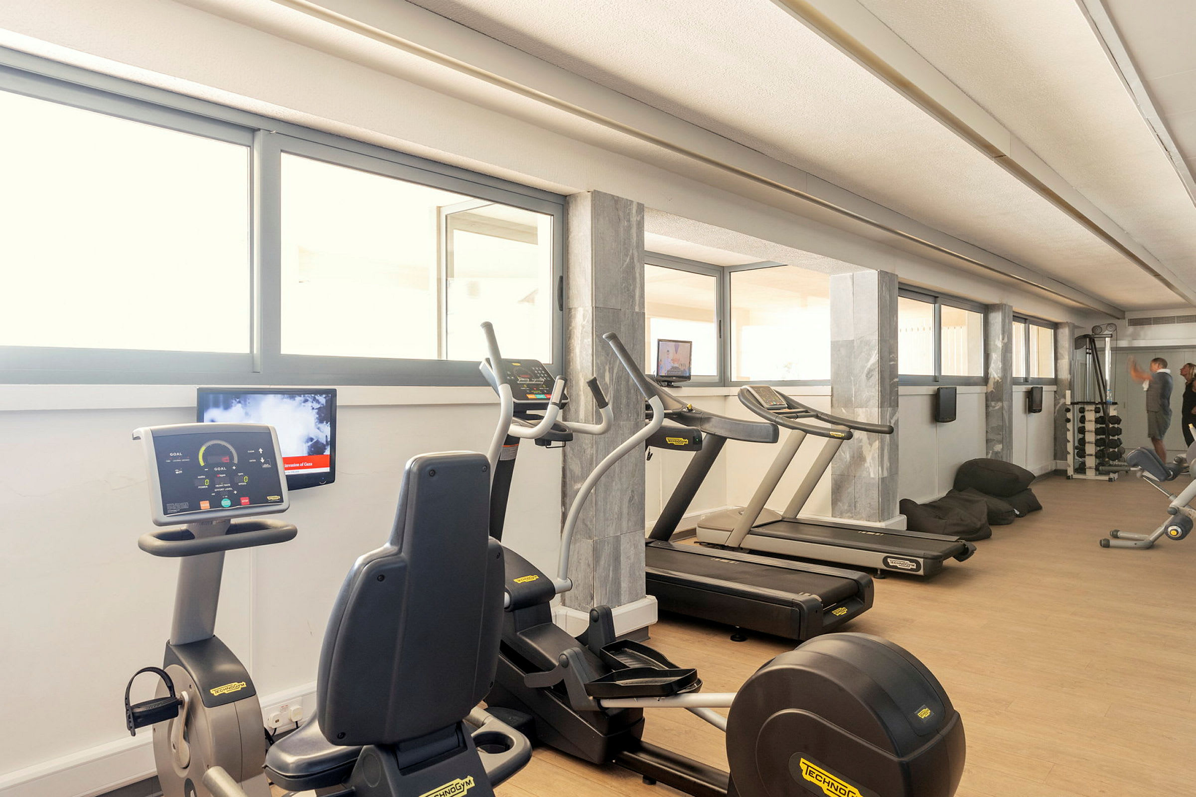Ett gym med träningsmaskiner och stora fönster. (AI-genererad text)