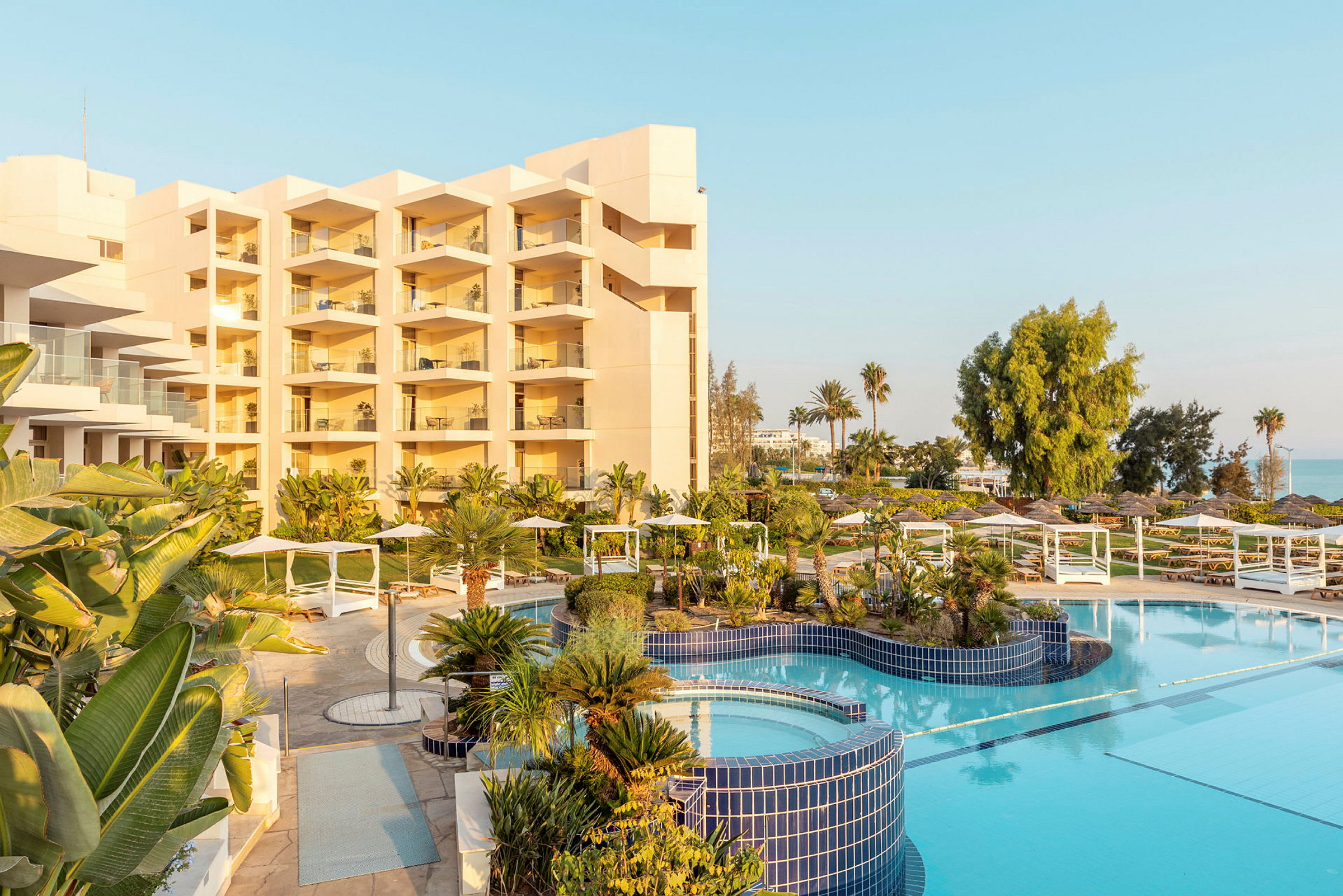 Hotellbyggnad med balkonger, poolområde och grönska. (AI-genererad text)