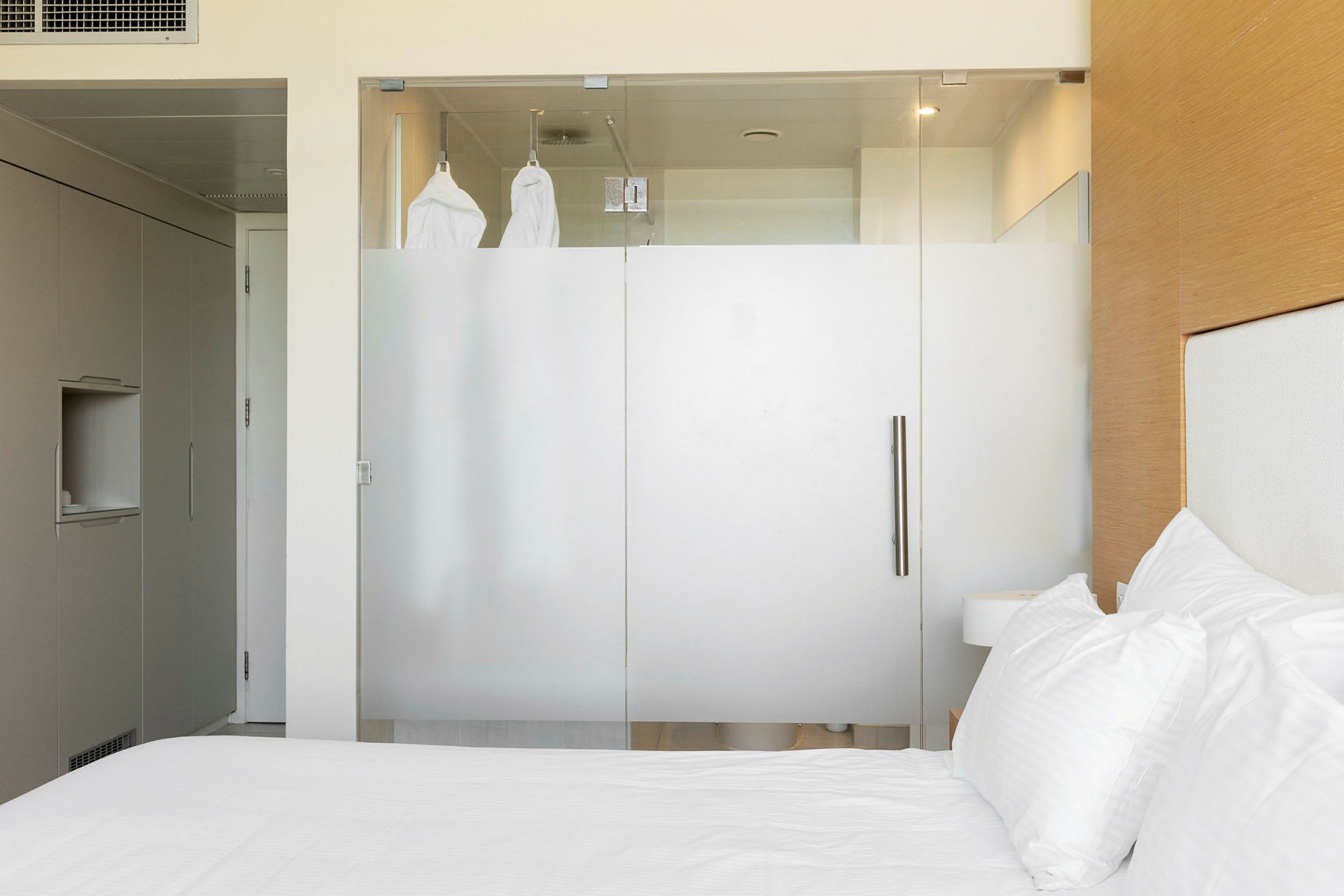 Ett hotellrum med en glasvägg som delar av badrummet. (AI-genererad text)