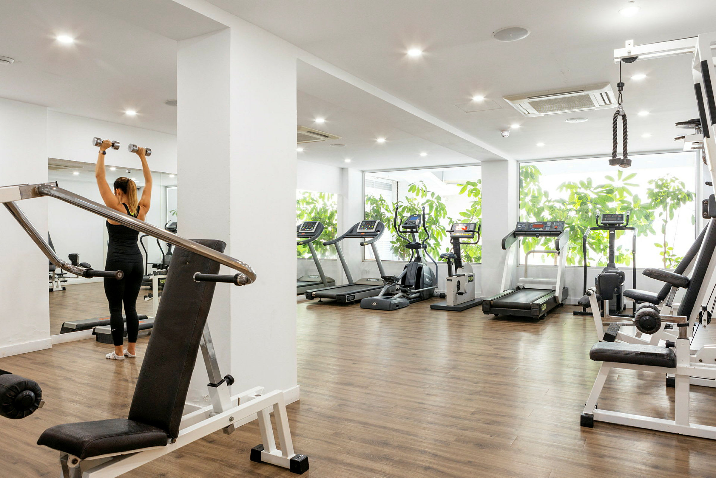 Ett gym med träningsmaskiner och en person som lyfter hantlar. (AI-genererad text)