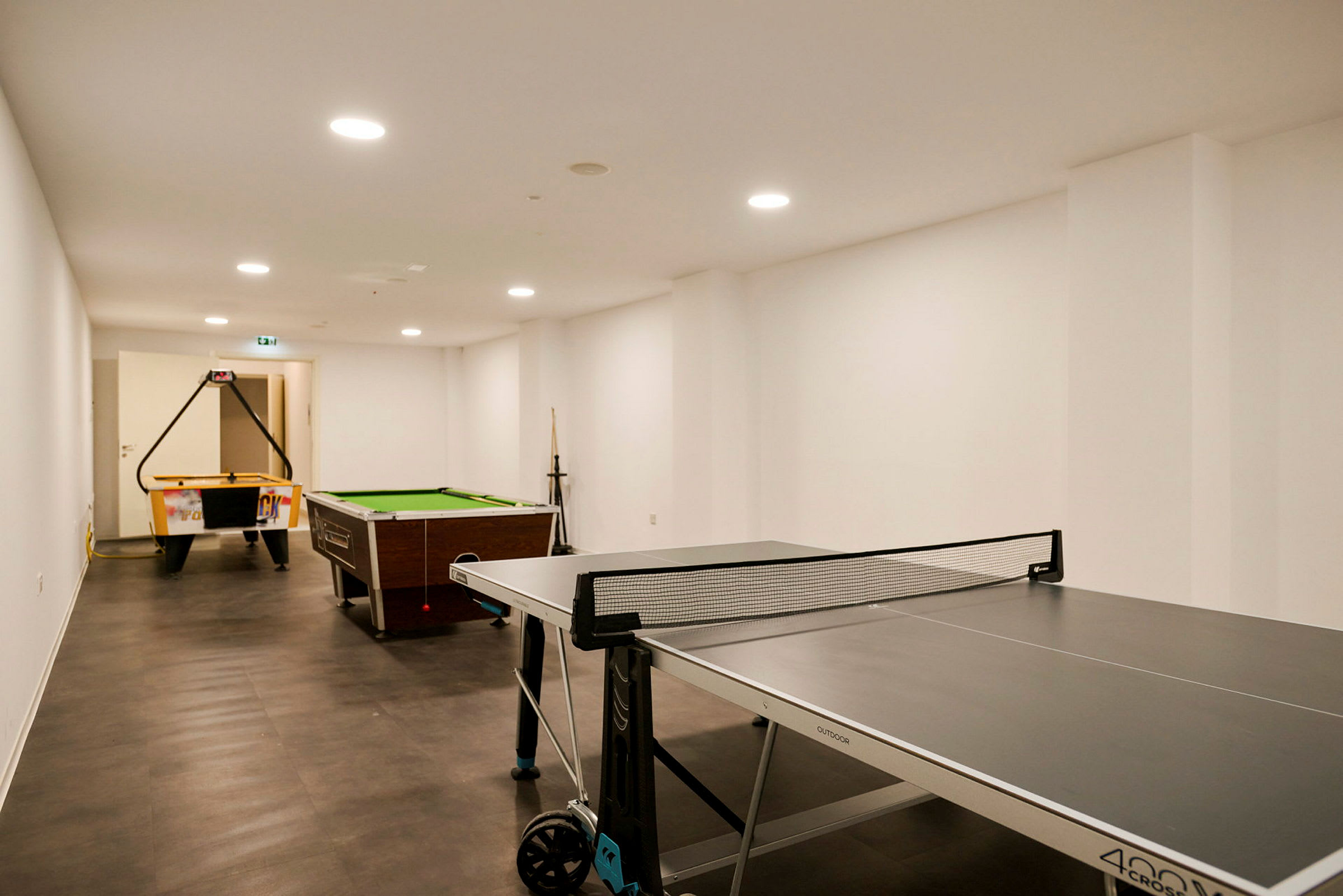 Ett spelrum med bordtennis, biljardbord och air hockey-bord. (AI-genererad text)