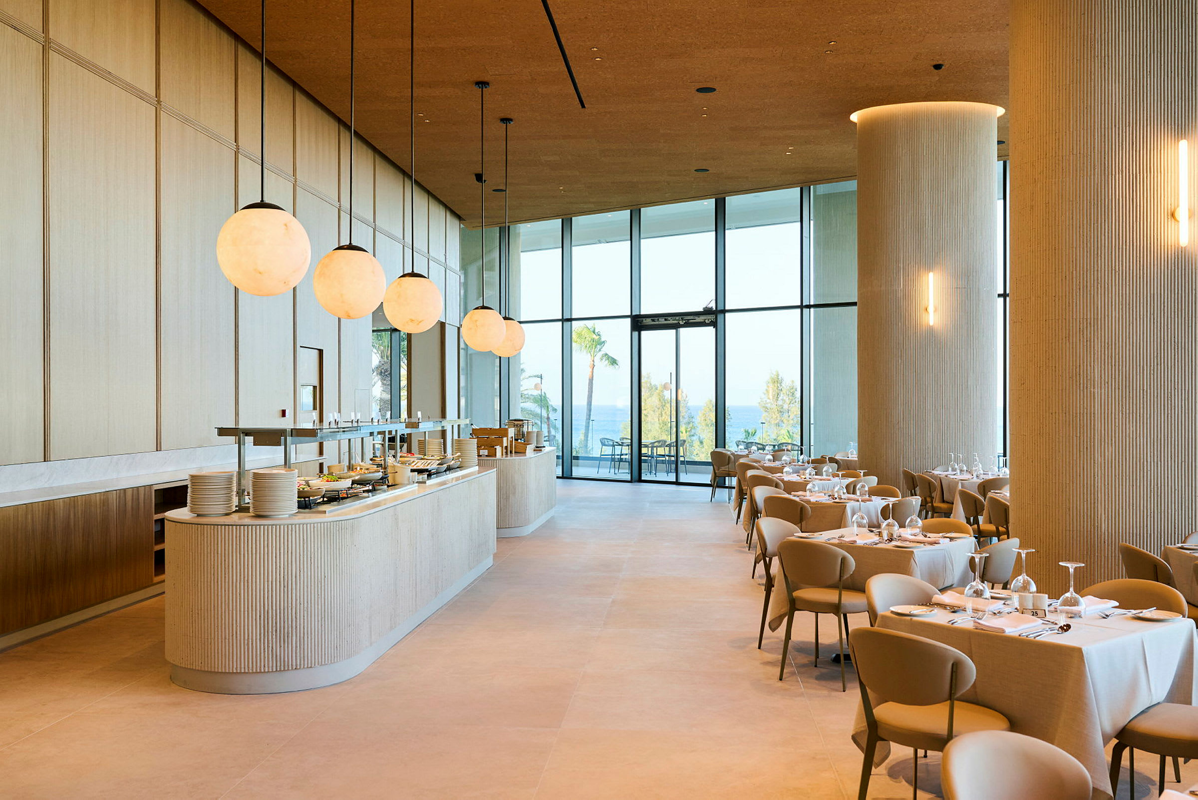 Ett modernt och ljust restaurangutrymme med dukade bord och stora fönster som vetter mot en utomhusvy. (AI-genererad text)