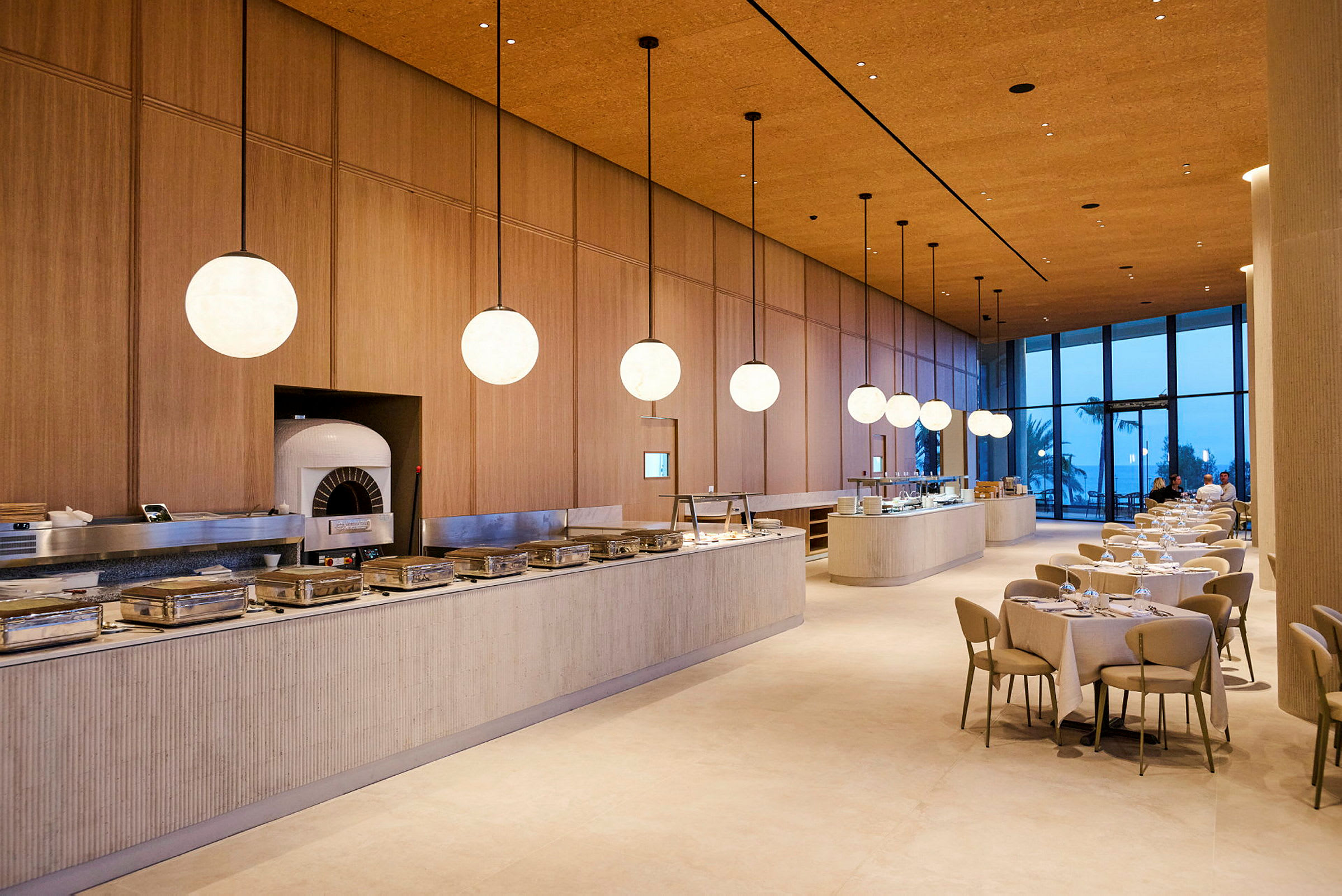 En elegant restaurang med moderna möbler och stora fönster och serveringsbord uppställda. (AI-genererad text)