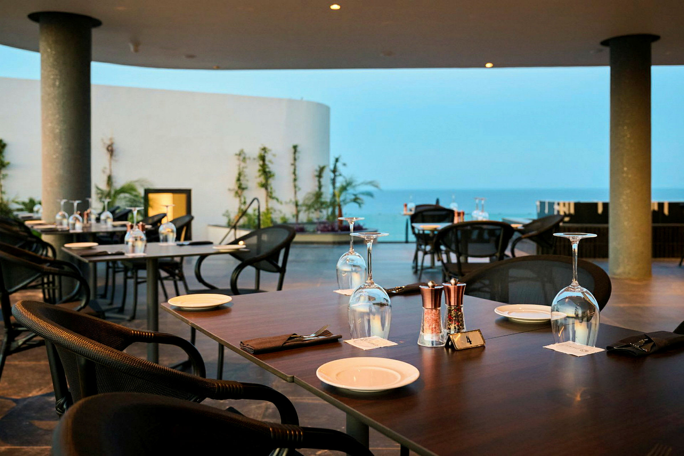Restaurang med dukade bord på en terrass med utsikt över havet. (AI-genererad text)
