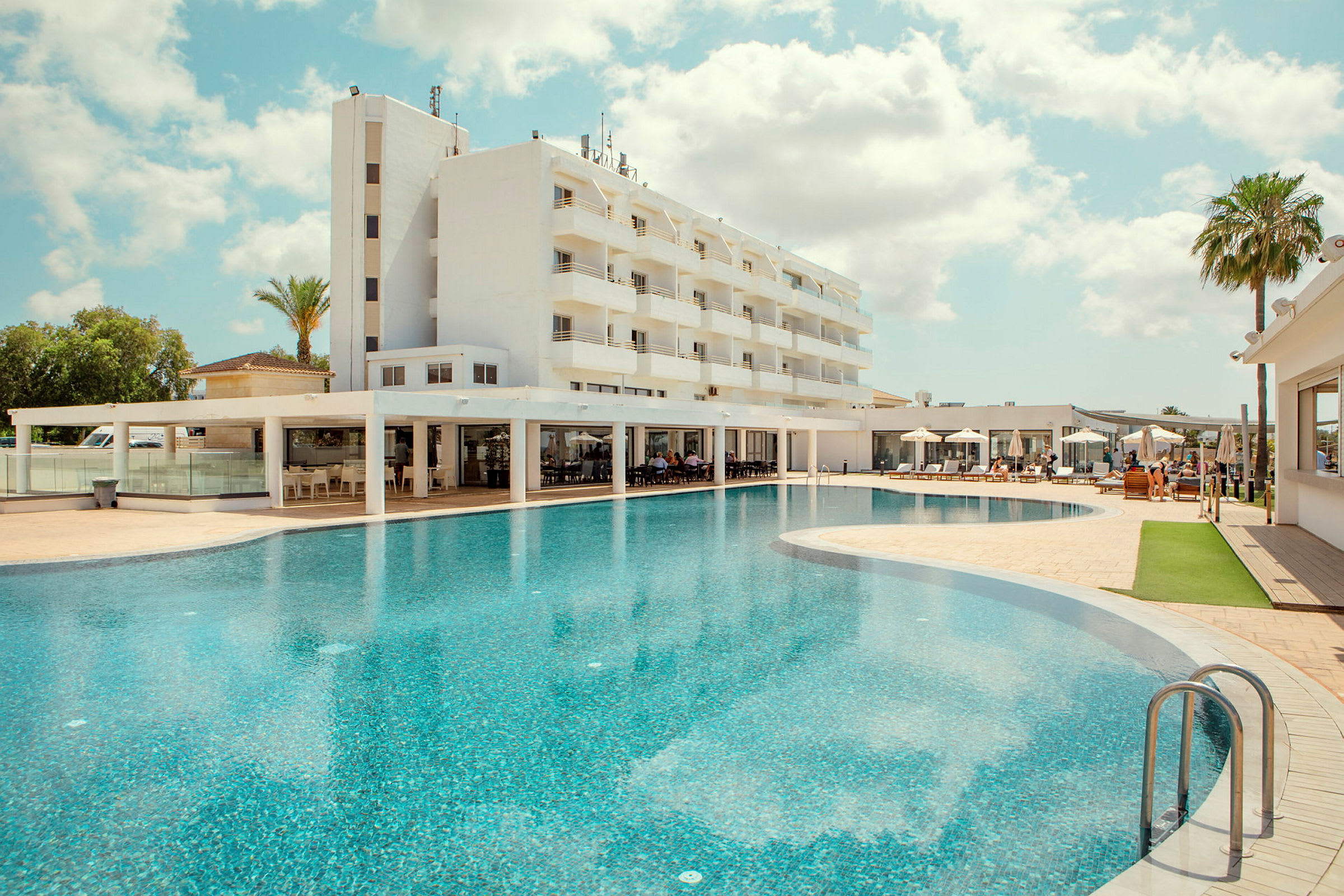 Hotell med en stor pool och solstolar. (AI-genererad text)