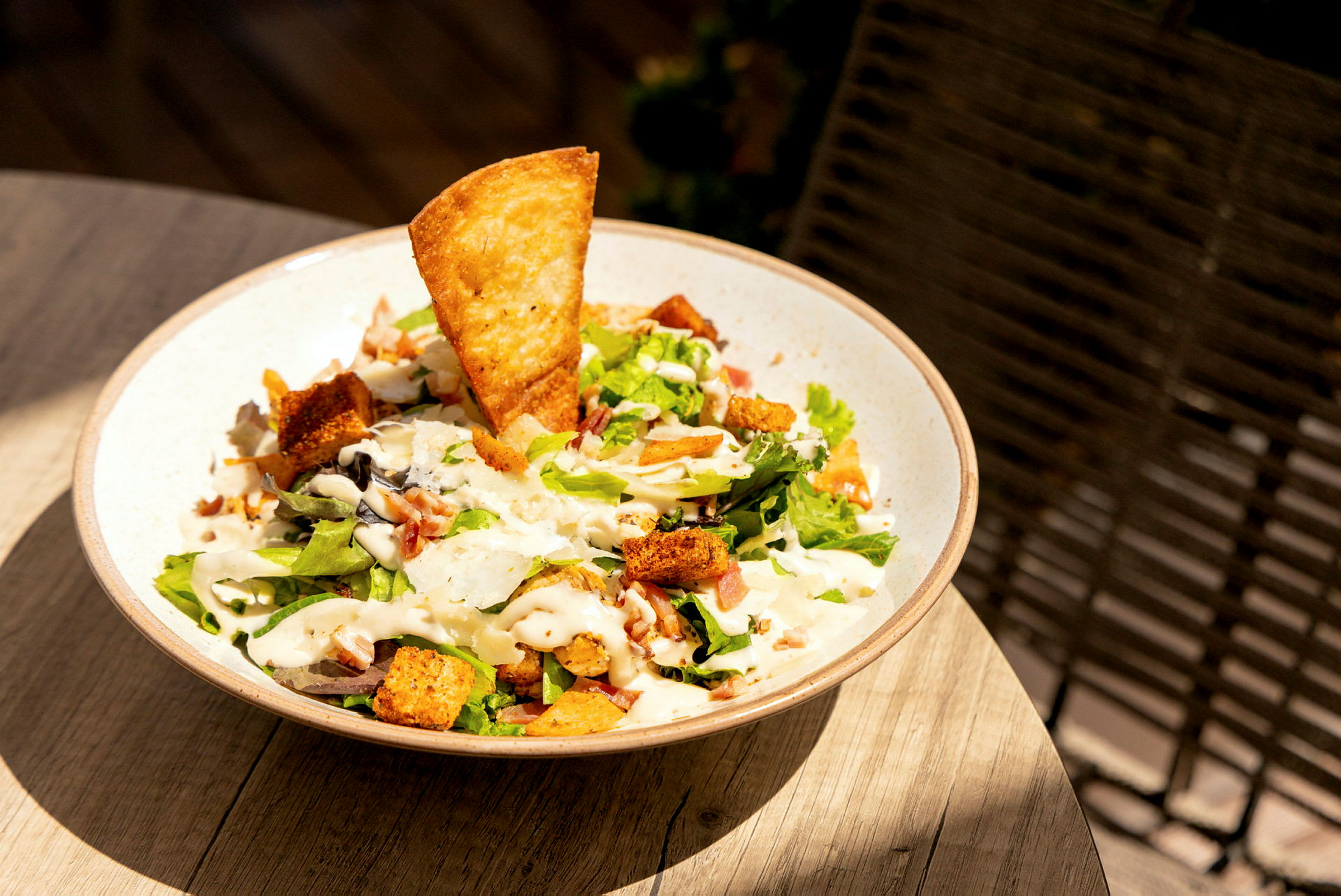 En skål med sallad som innehåller grönsaker, krutonger, ett krispigt bröd och dressing. (AI-genererad text)