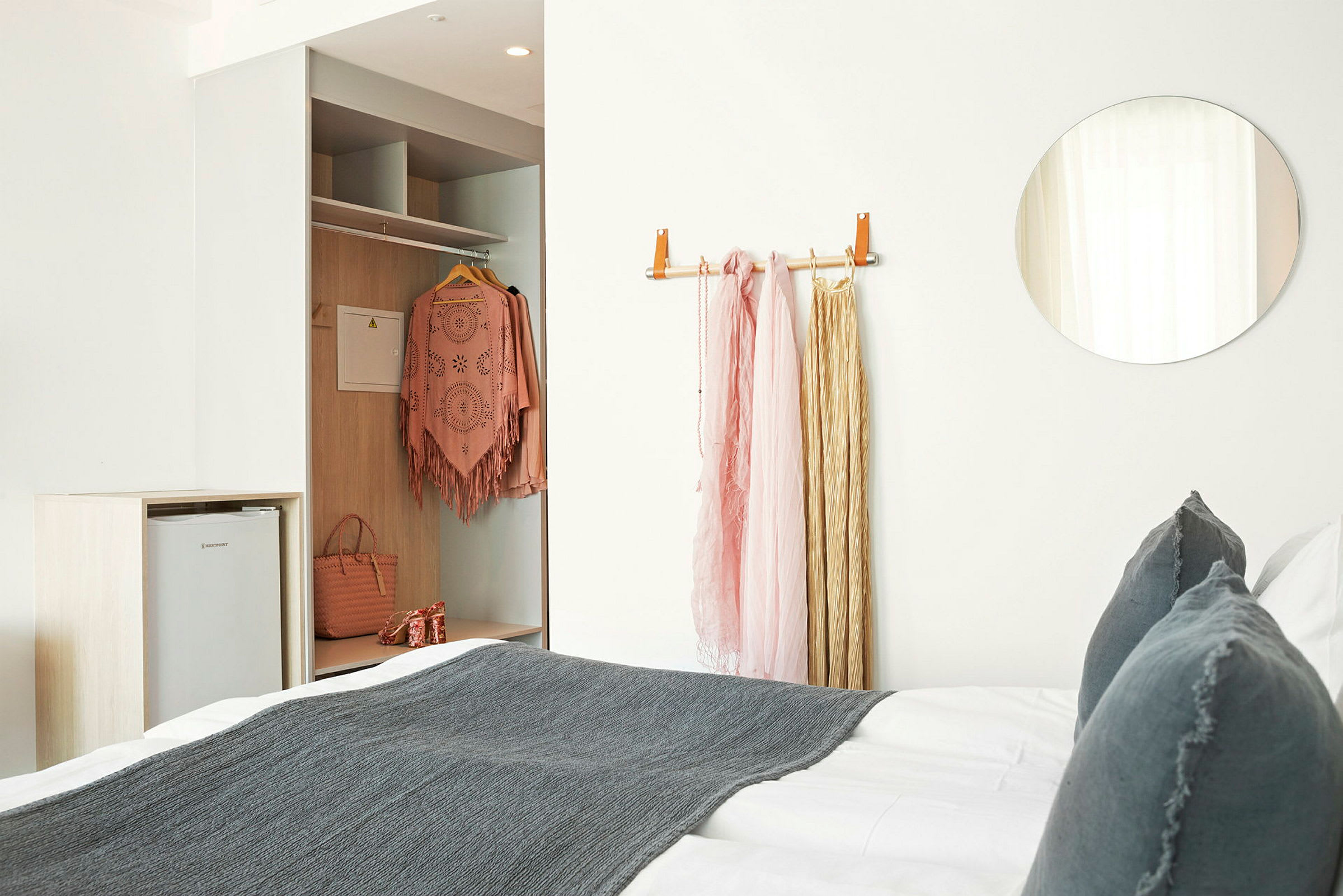 Ett hotellrum med en säng och garderob; klädesplagg är upphängda. (AI-genererad text)