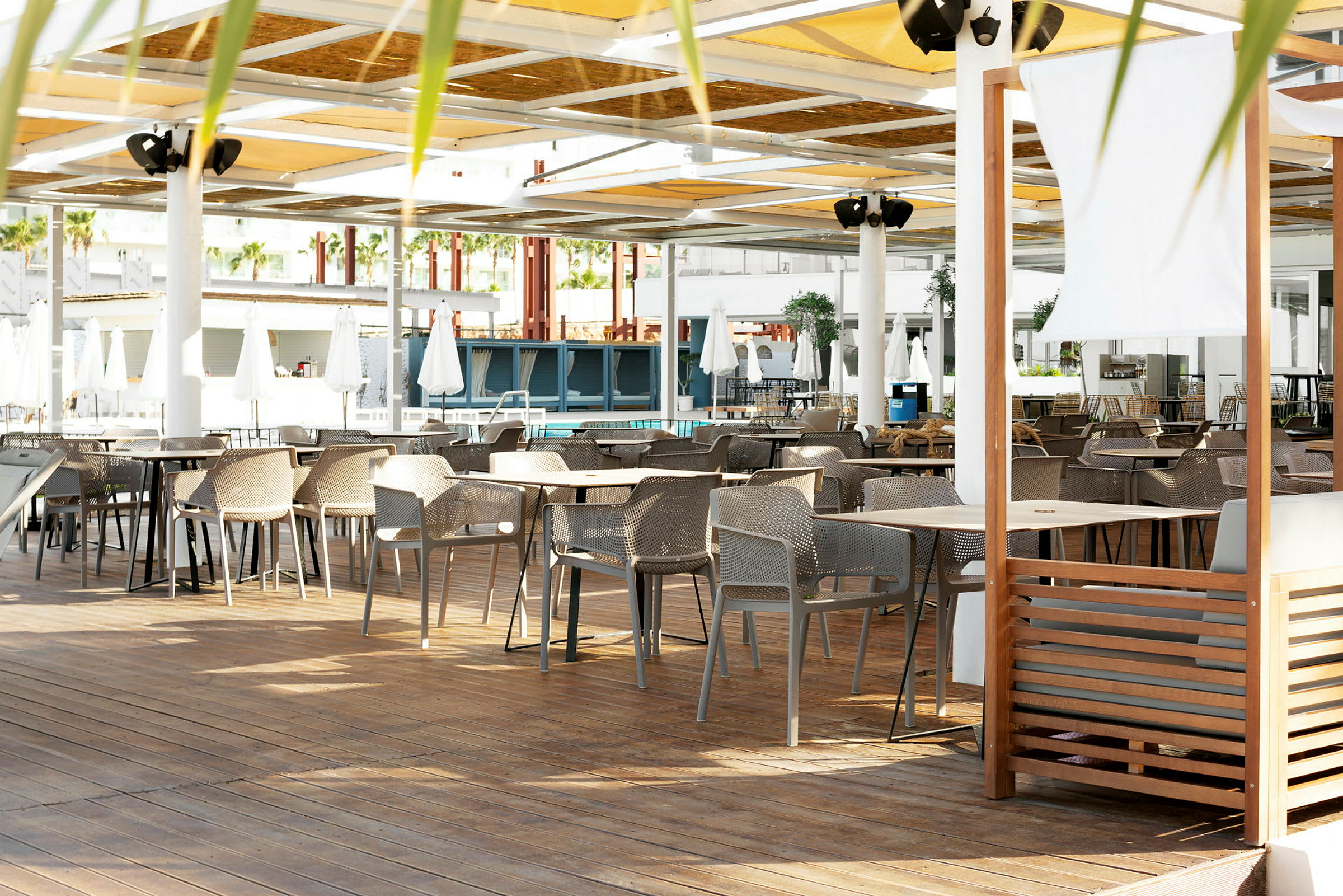 En sittgrupp med bord och stolar på en terrass med tak. (AI-genererad text)