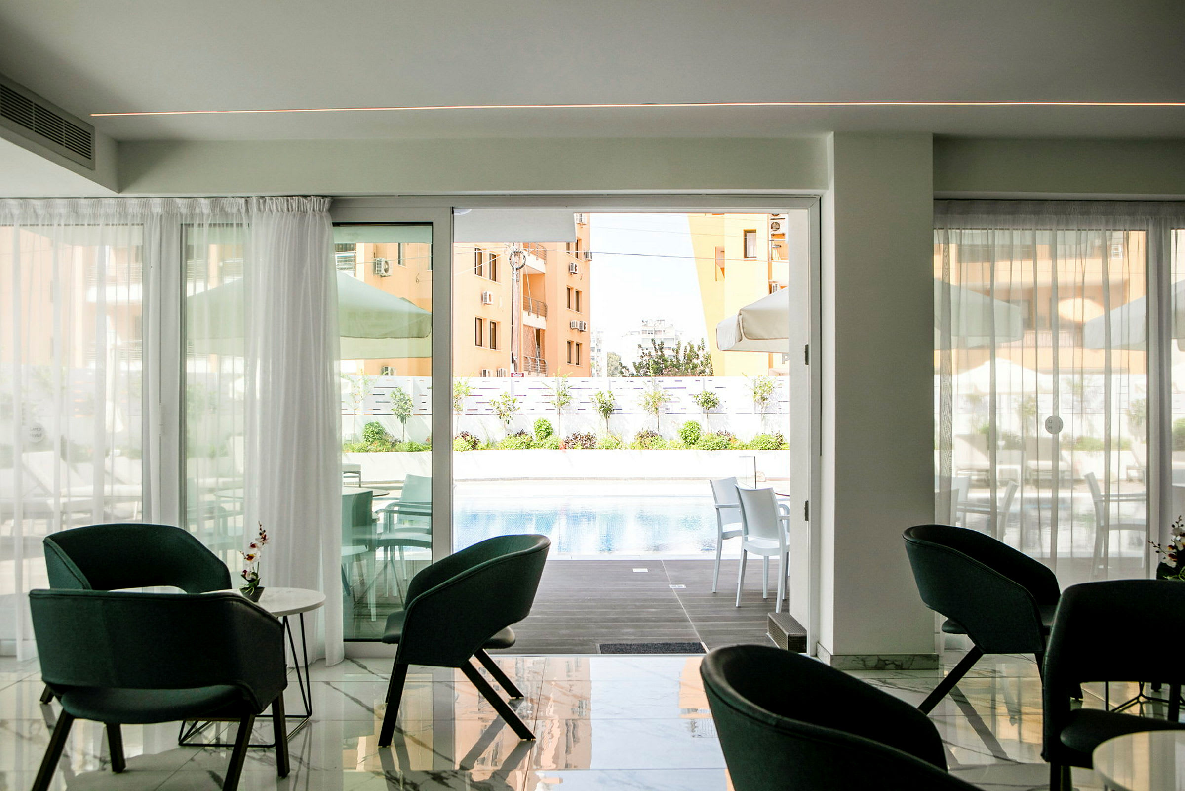 Ett rum med sittplatser framför en glasdörr som leder ut till en pool och en uteplats. (AI-genererad text)