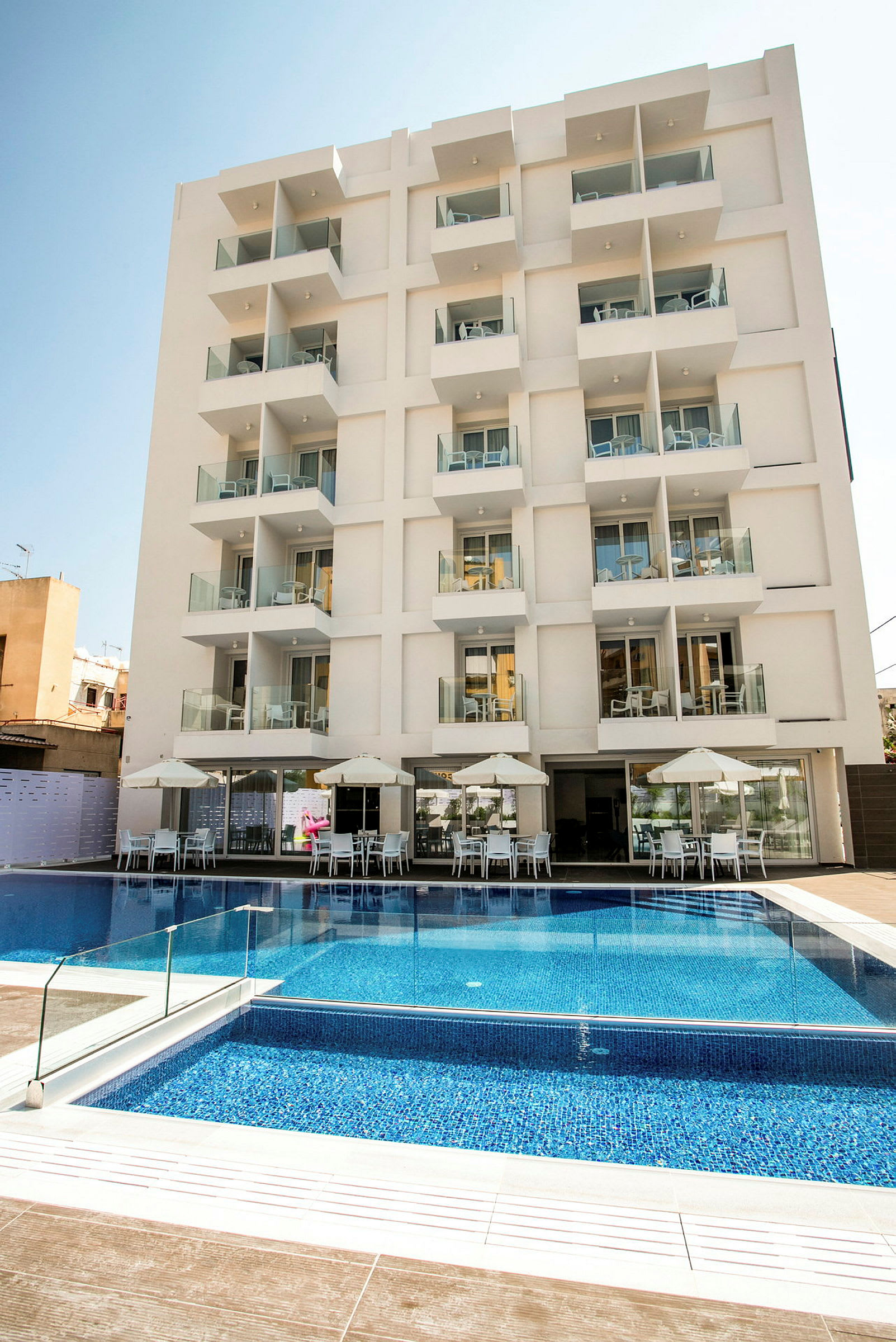 Bild av ett modernt hotell med flera balkonger och en pool framför. (AI-genererad text)