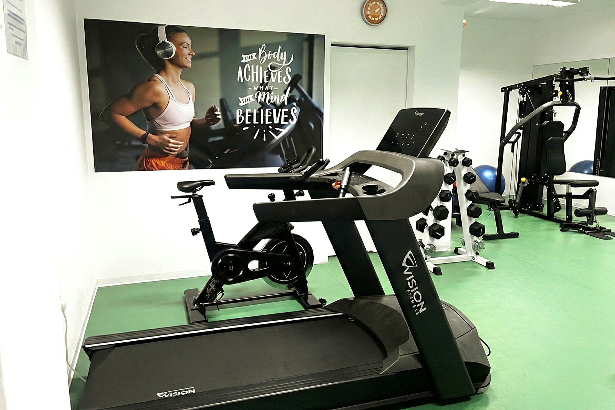 Ett gym med en löpband, träningscykel och styrkeutrustning. (AI-genererad text)