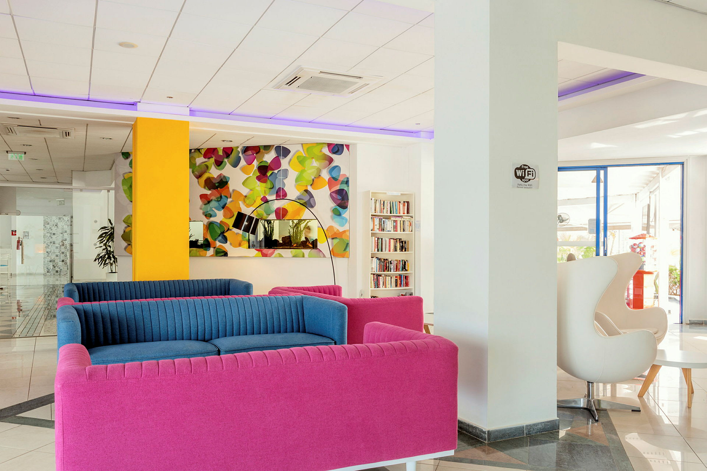 En modern lobby med färgglada soffor och ett färgstarkt konstverk. (AI-genererad text)