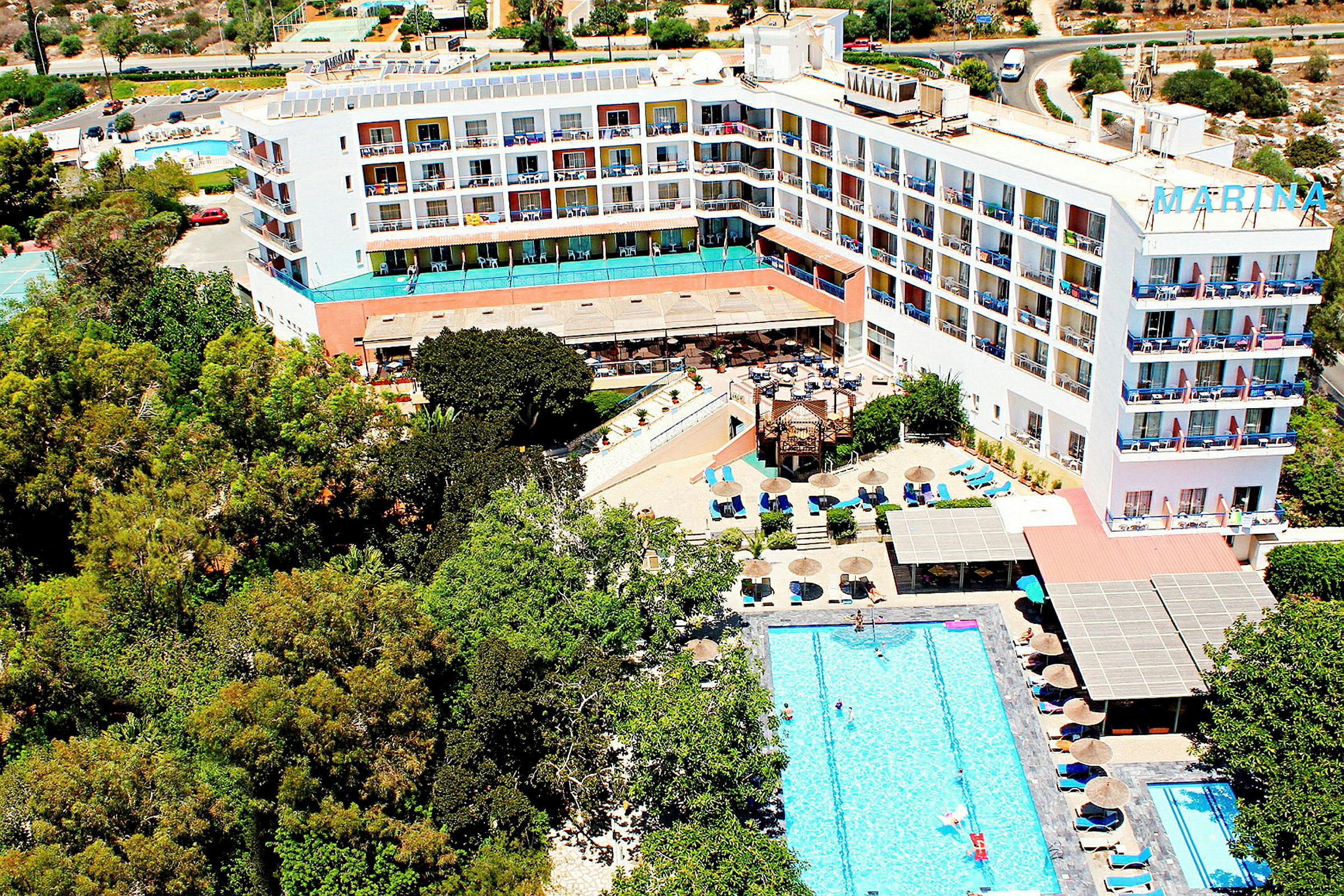 Flygvy av hotell med pool och omgivande grönska. (AI-genererad text)