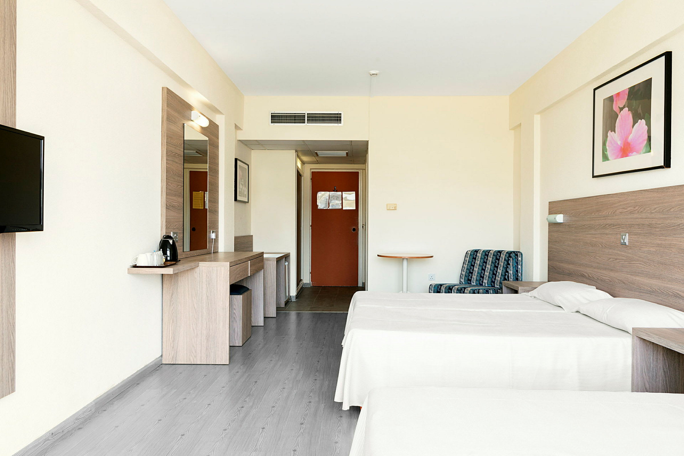 Bilden visar ett hotellrum med två enkelsängar, en sittplats och ett skrivbord. (AI-genererad text)