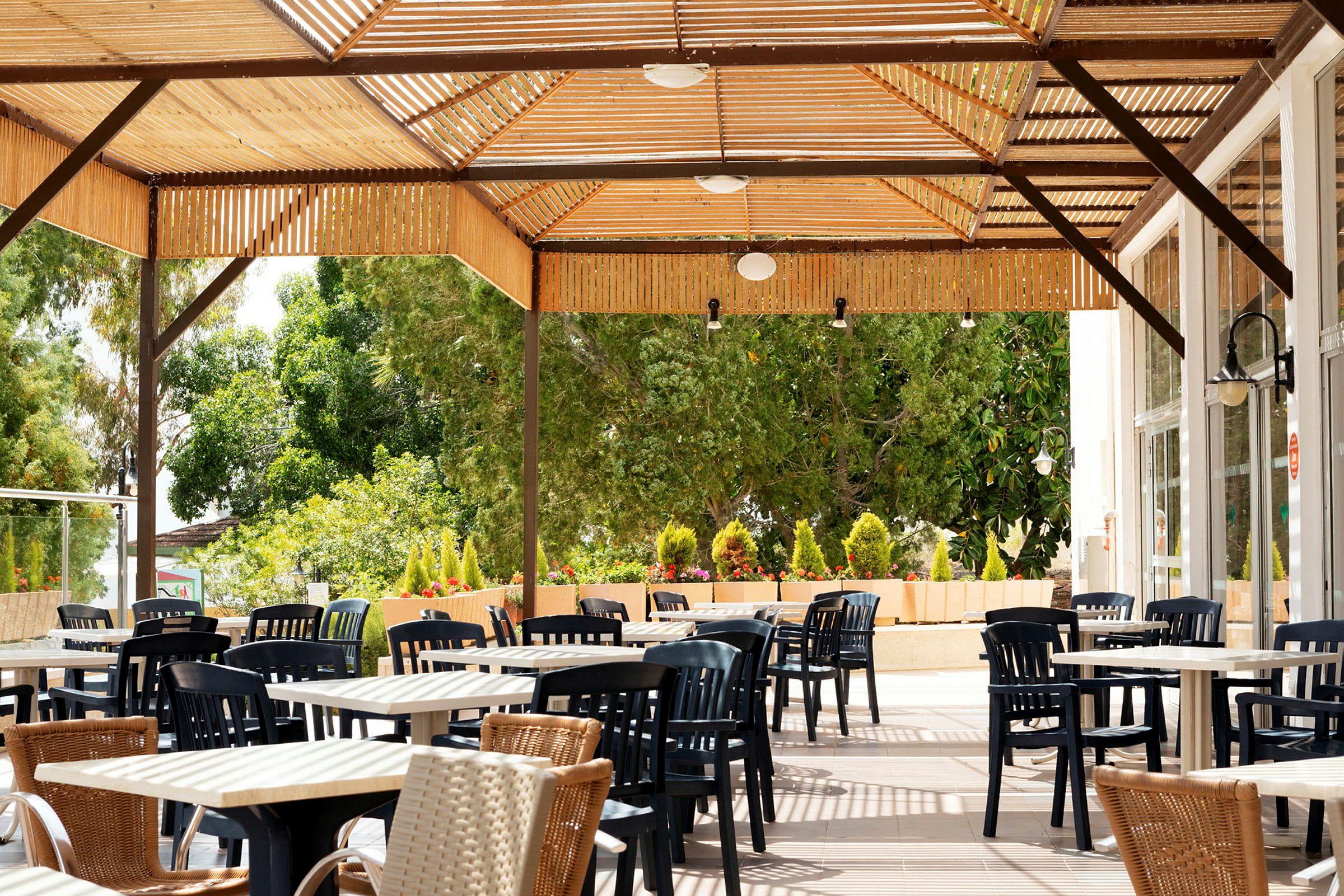 Utomhus sittgrupp med bord och stolar under en träpergola, omgiven av grönska. (AI-genererad text)