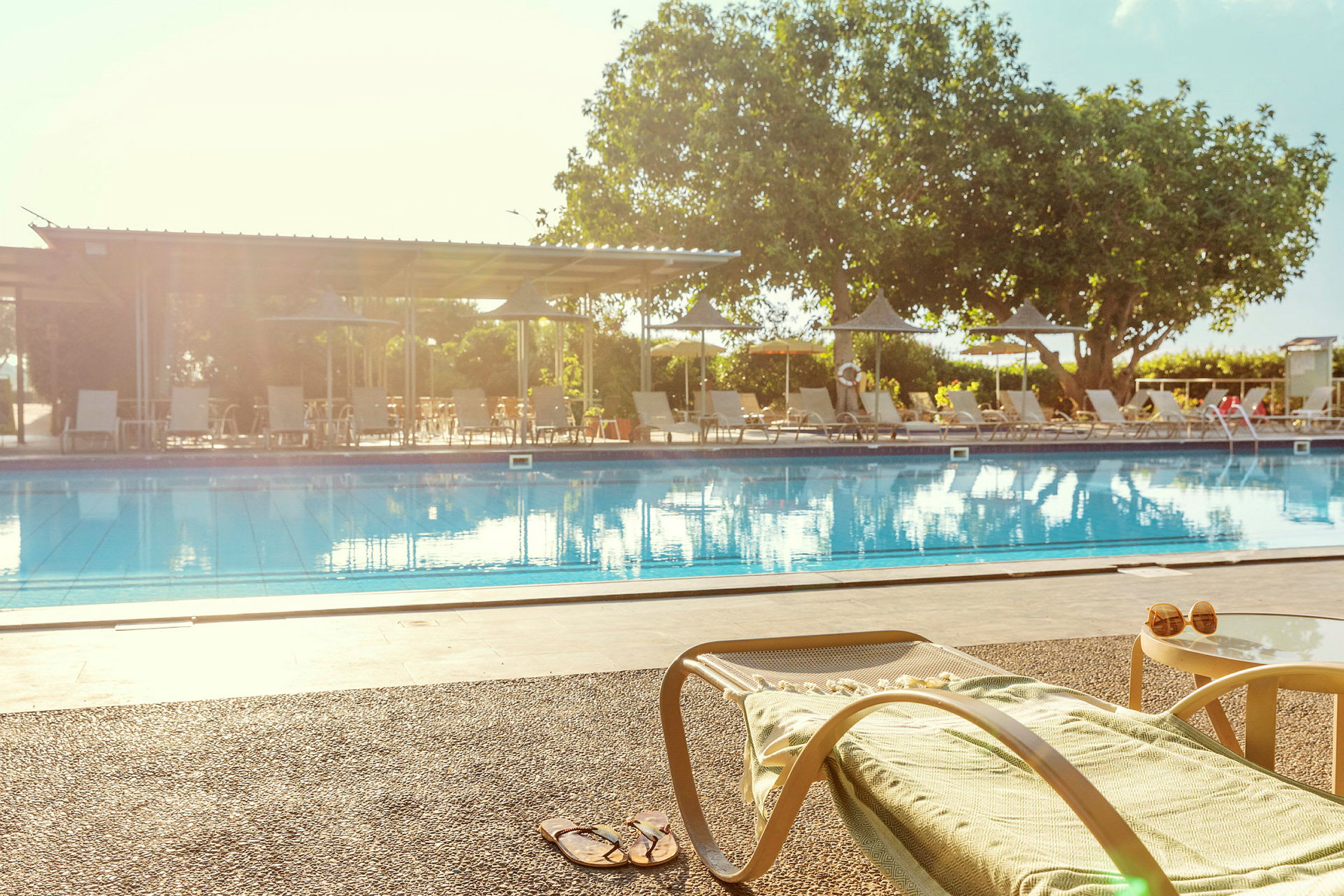 En solstol och ett bord vid kanten av en pool. (AI-genererad text)