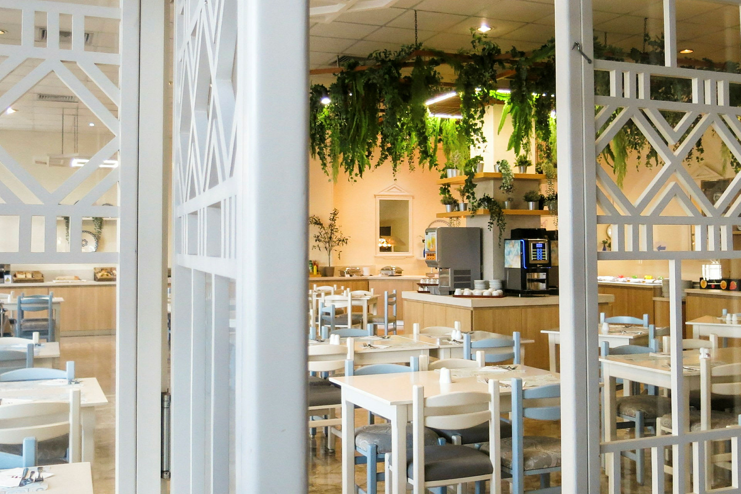 En restaurang med bord och stolar, samt en dekorerad buffé och hängande grönska. (AI-genererad text)