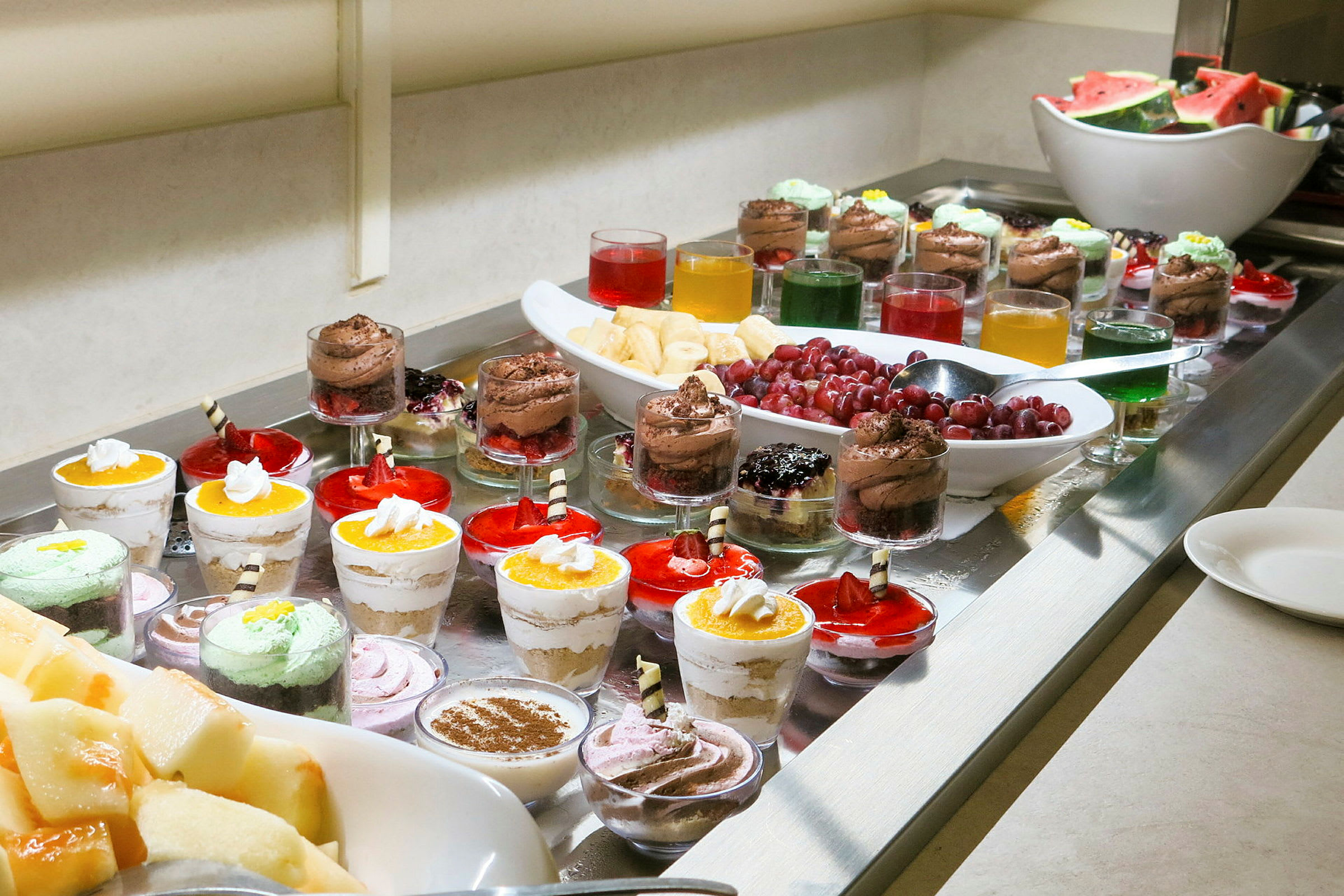 Bild på ett dessertbord med olika små desserter och frukt. (AI-genererad text)