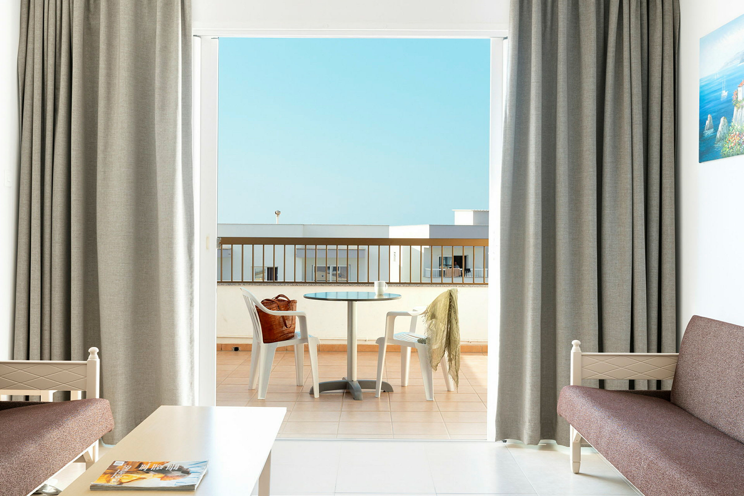Ett hotellrum med utsikt över en balkong med ett bord och stolar. (AI-genererad text)