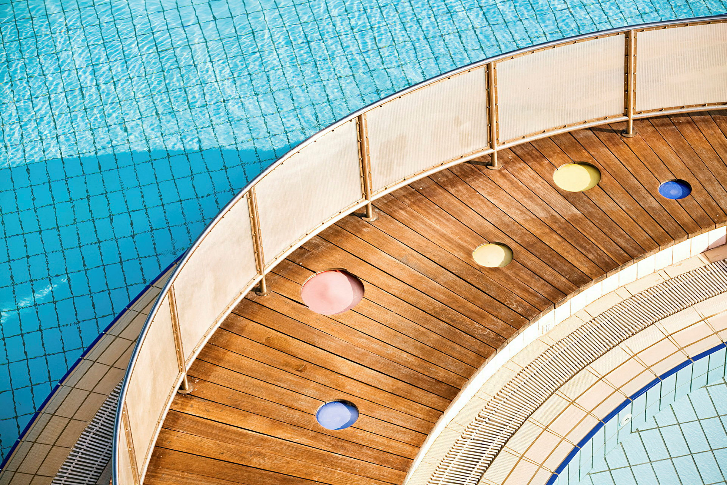 En träbrygga med färgade hål intill en swimmingpool. (AI-genererad text)