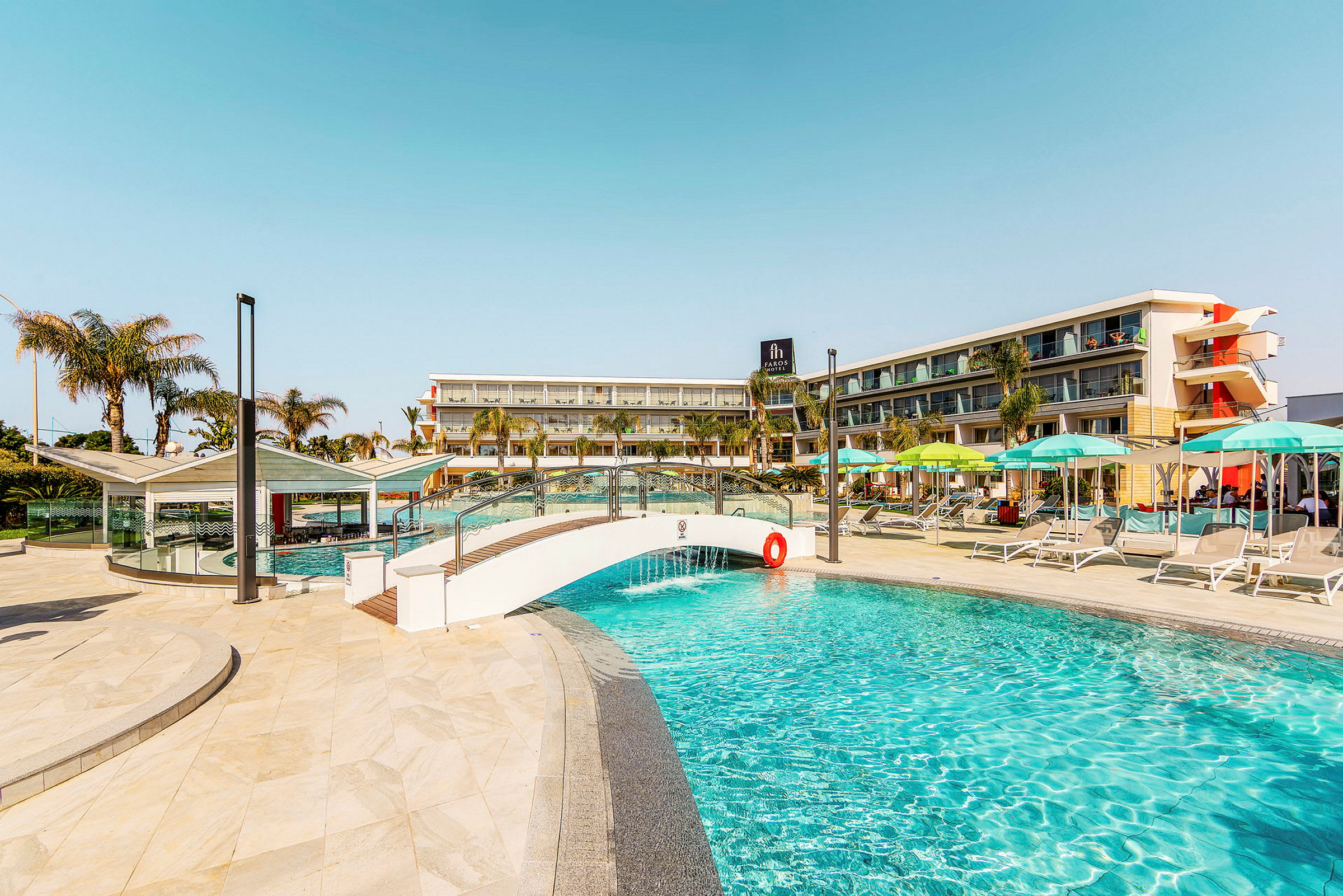 Bild av en pool, med en liten bro och hotellbyggnad i bakgrunden. (AI-genererad text)