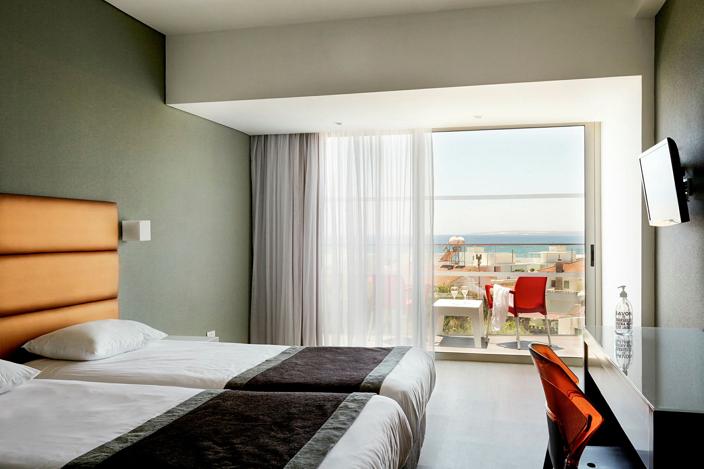 Hotellrum med två enkelsängar och balkong med havsutsikt. (AI-genererad text)