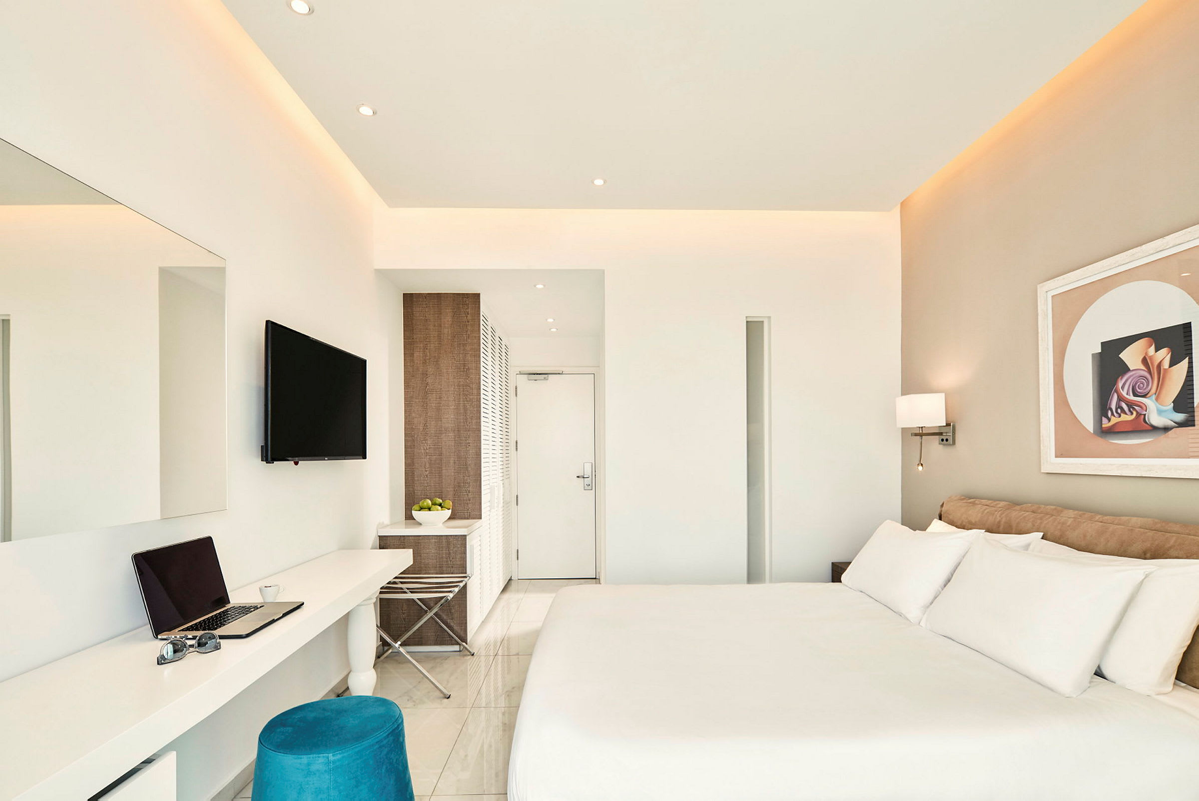 Ett modernt hotellrum med en stor säng, ett skrivbord med en laptop, en väggmonterad TV och modern inredning. (AI-genererad text)