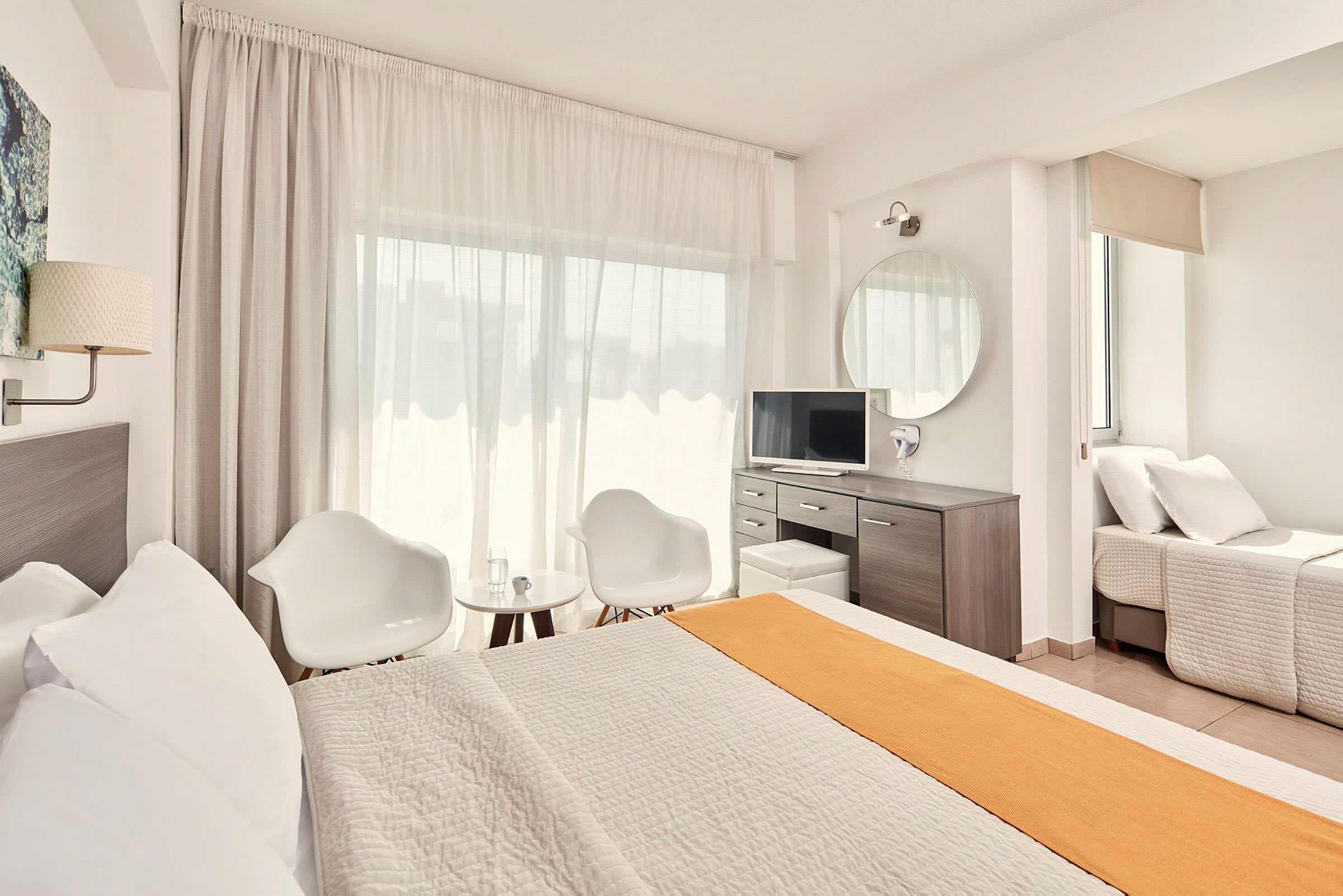 Ett ljust och modernt hotellrum med säng, sittgrupp och skrivbord. (AI-genererad text)