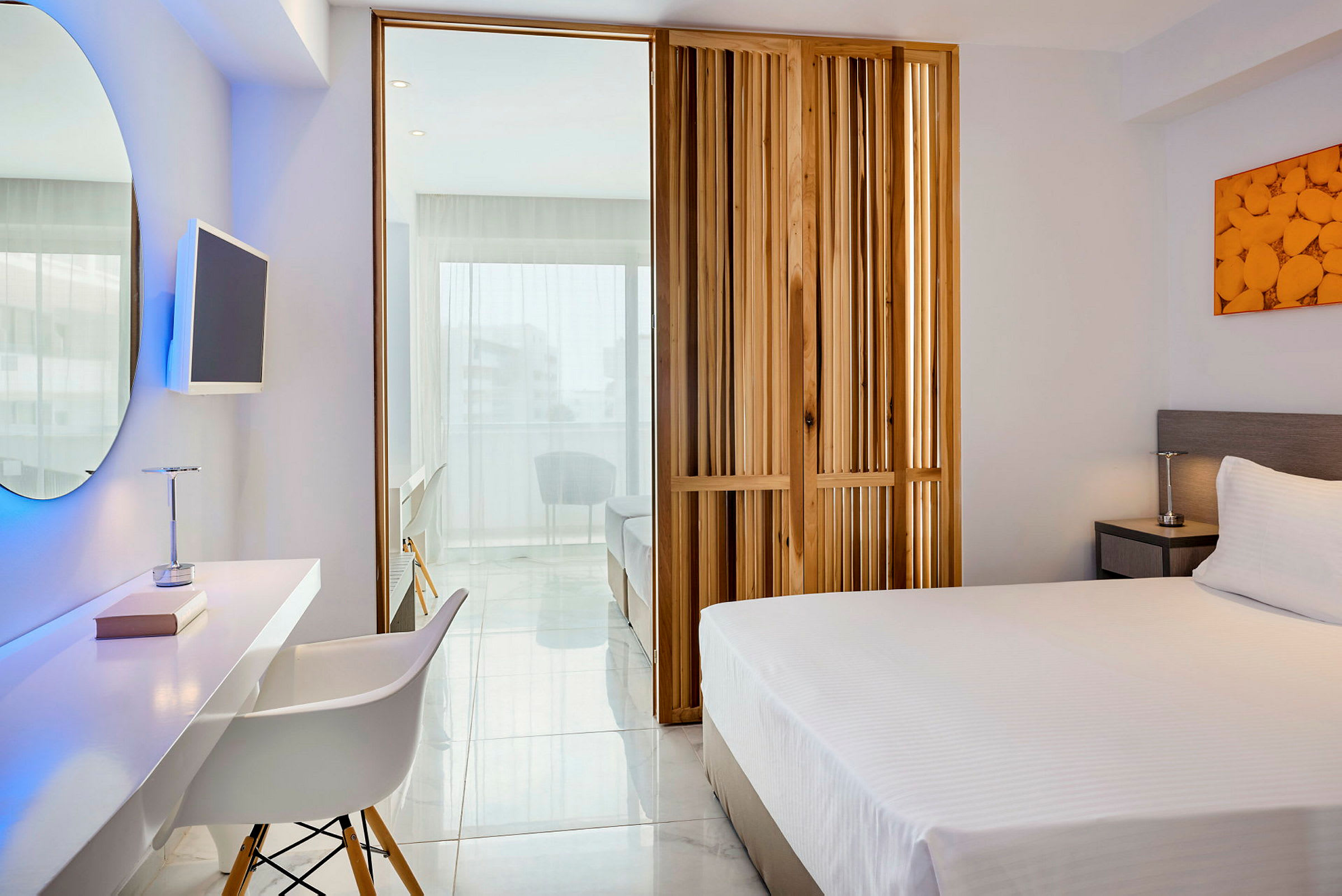 Ett modernt hotellrum med en säng, skrivbord, en TV och en sittgrupp i ljus inredning. (AI-genererad text)