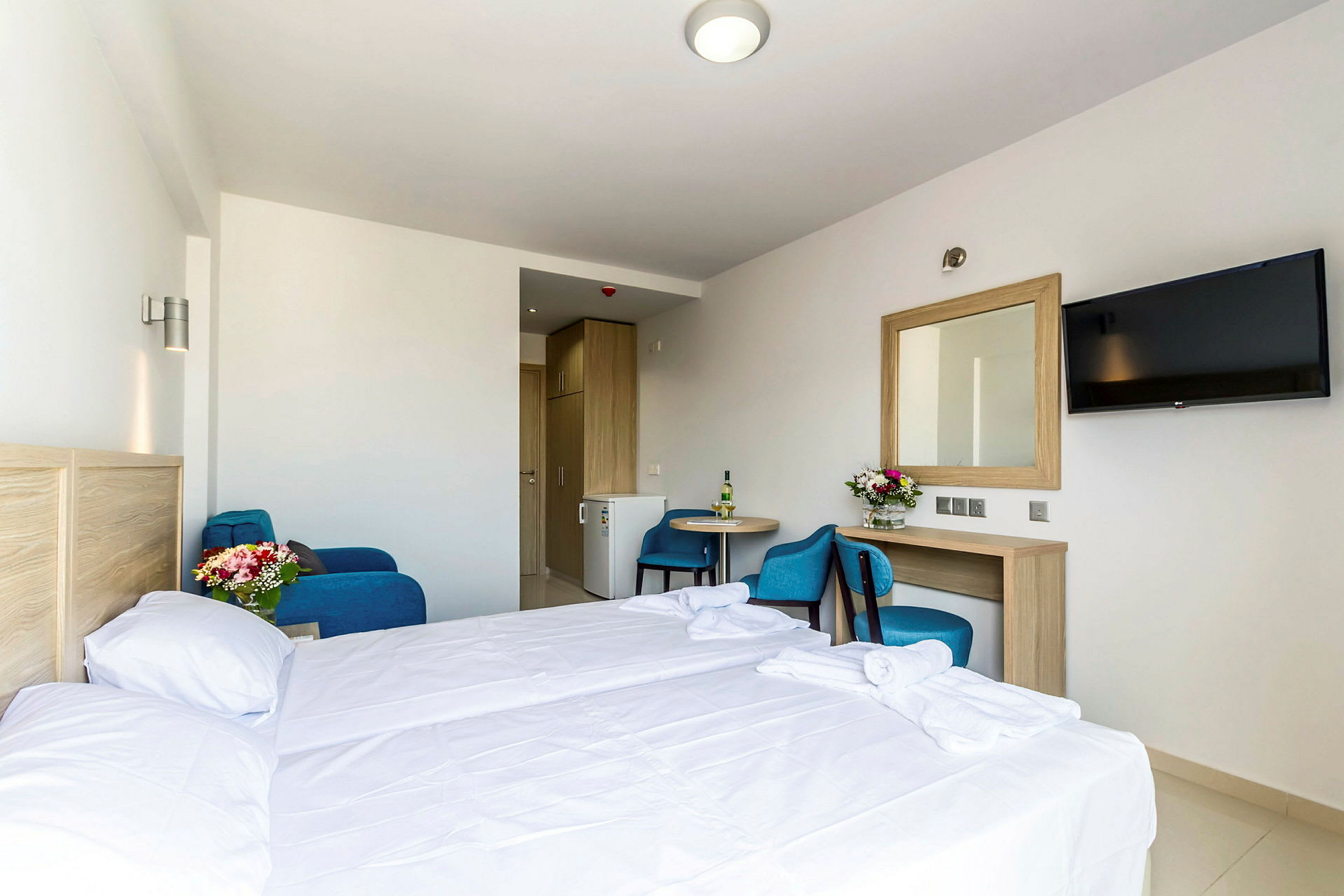 Hotellrum med säng, bord, stol, spegel och TV. (AI-genererad text)