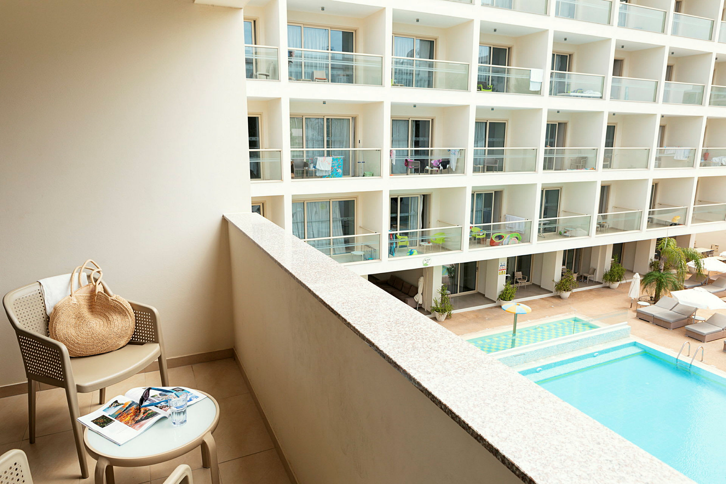 En hotellbalkong med utsikt över en pool och andra balkonger. (AI-genererad text)