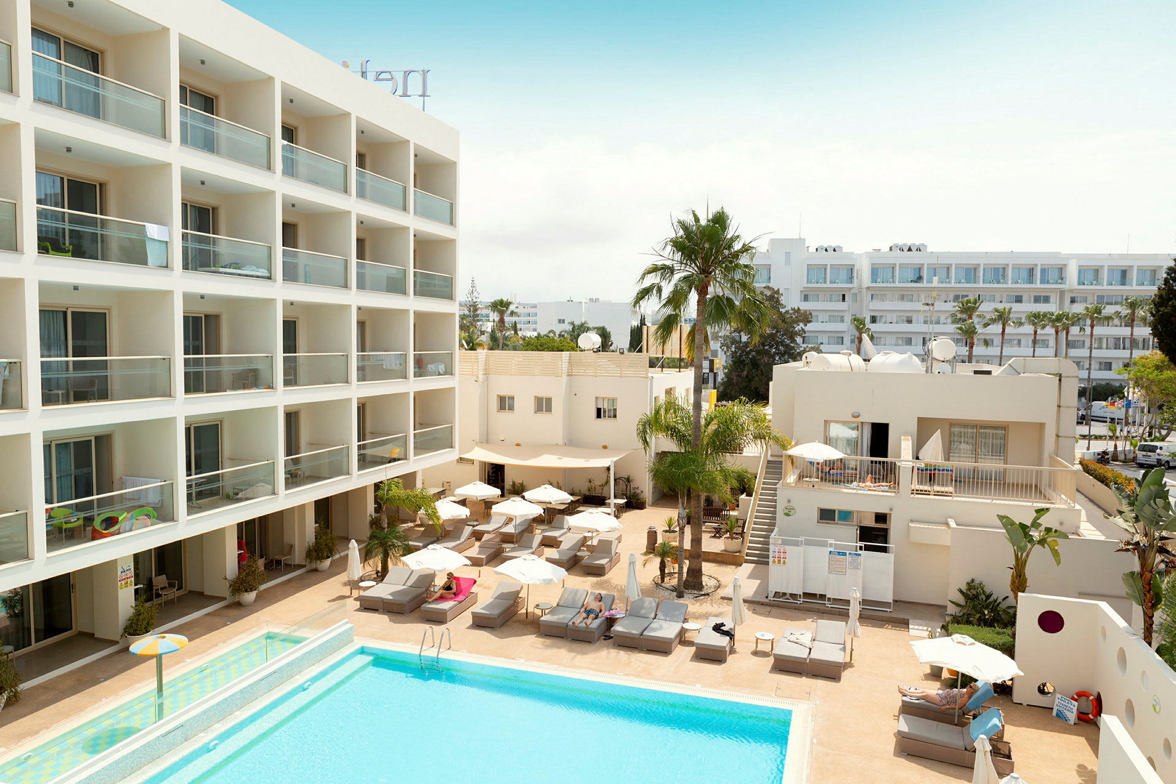 Hotellområde med pool, solstolar och byggnader. (AI-genererad text)