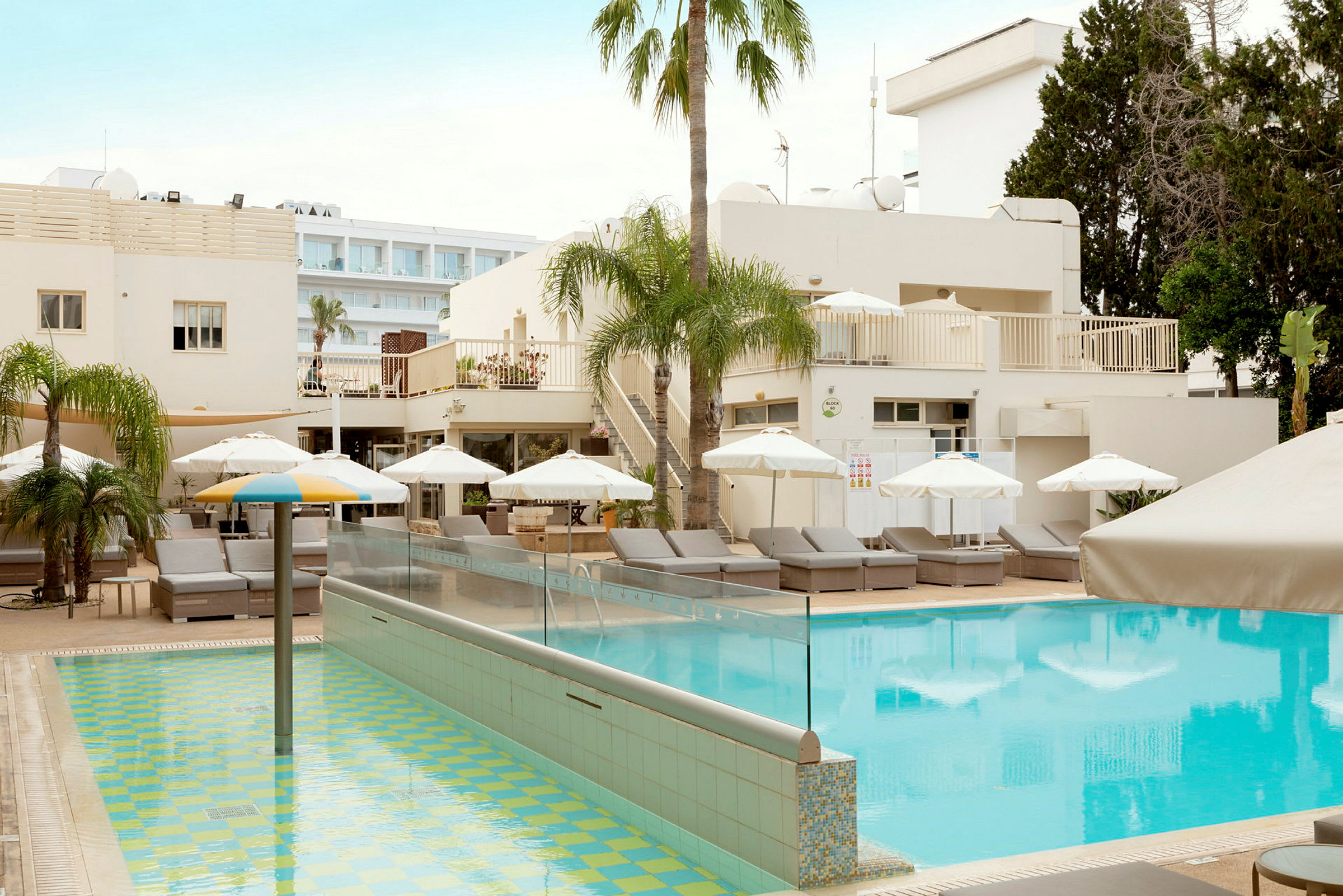 Poolområde med solstolar, parasoller och palmer vid ett hotell. (AI-genererad text)