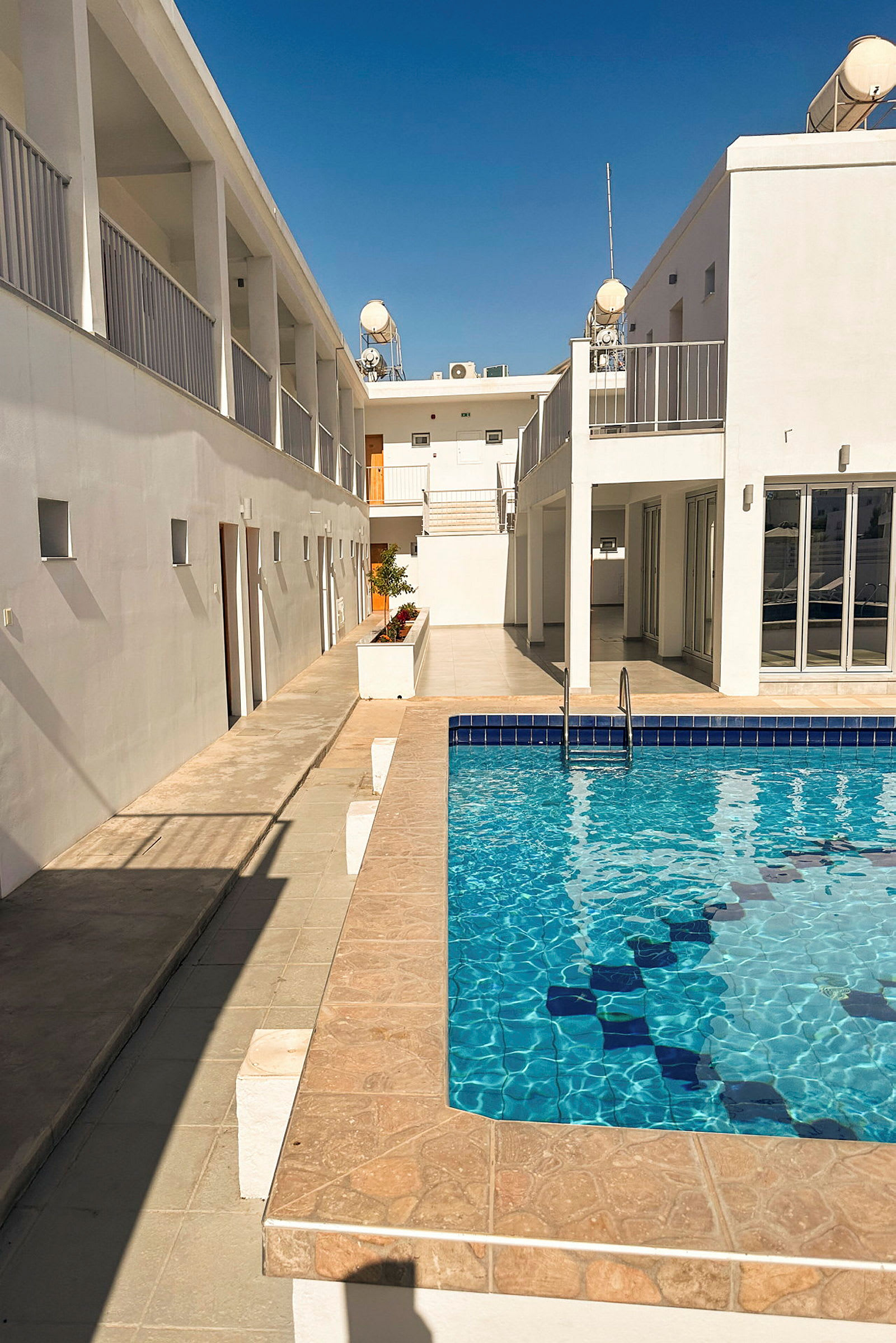 Bild av ett hotellområde med vit byggnad och pool. (AI-genererad text)