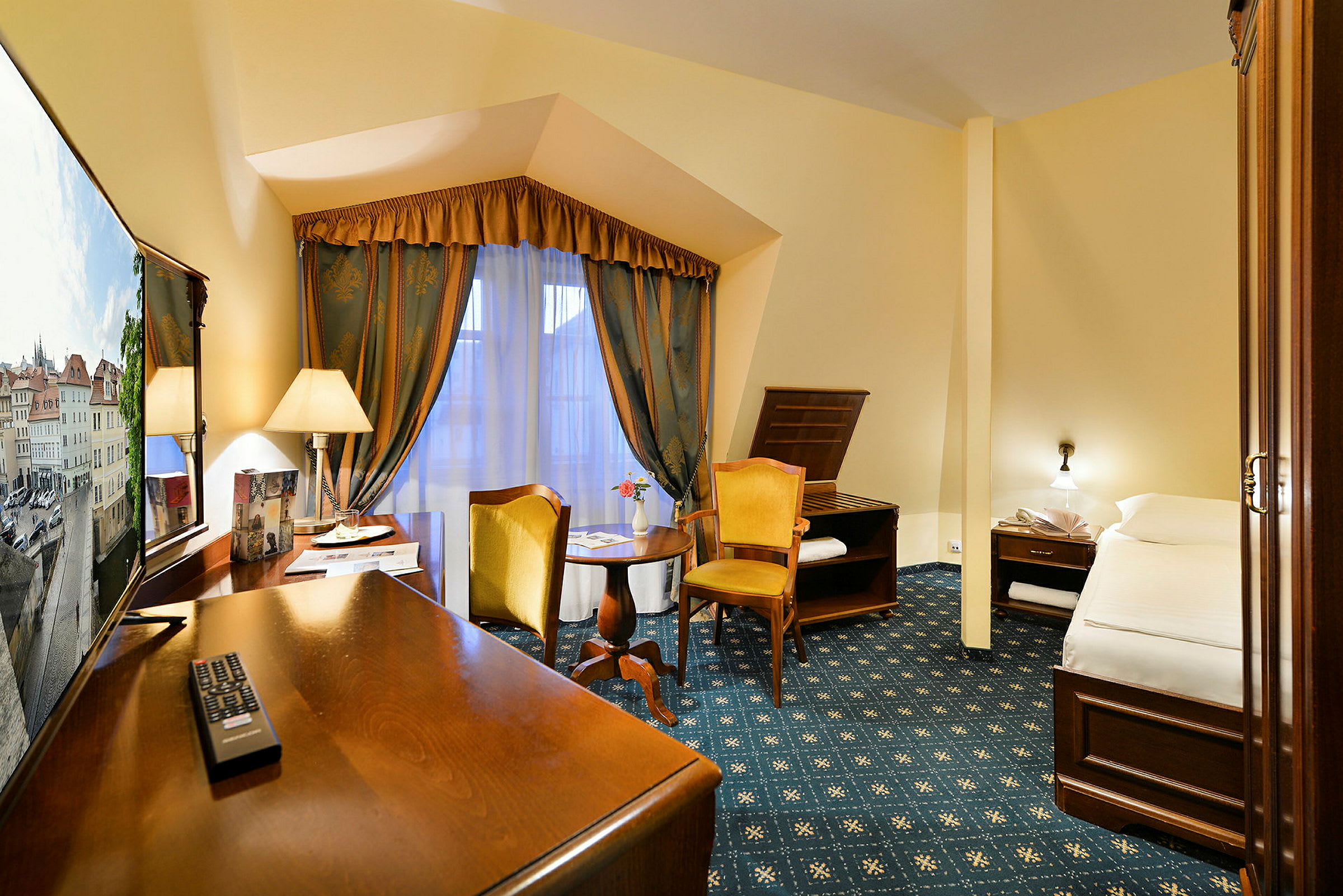 Ett hotellrum med skrivbord, stol, säng och fönster med draperier. (AI-genererad text)