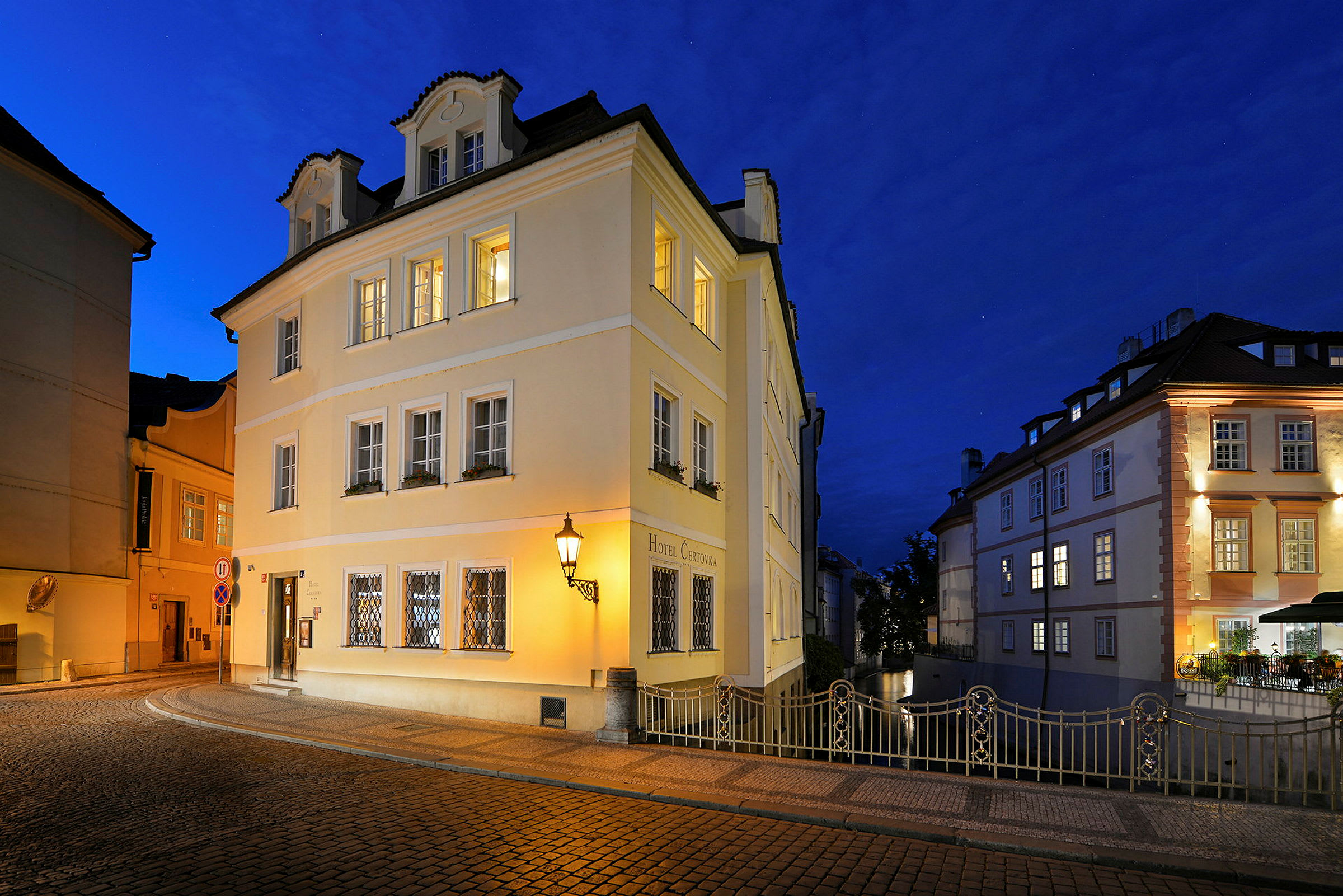En byggnad upplyst på kvällen, omgiven av gatlyktor och kullerstensgator. (AI-genererad text)