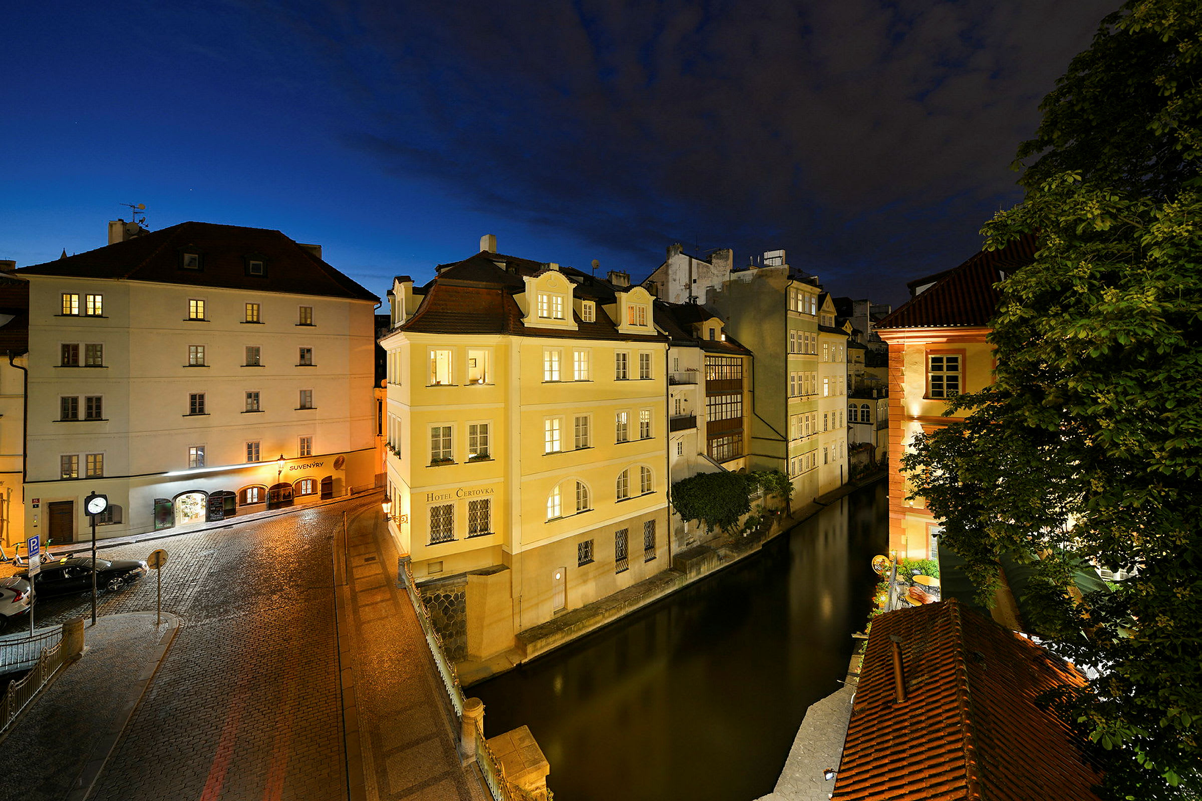 En nattlig stadsbild med upplysta byggnader längs en kanal och en kullerstensgatan. (AI-genererad text)