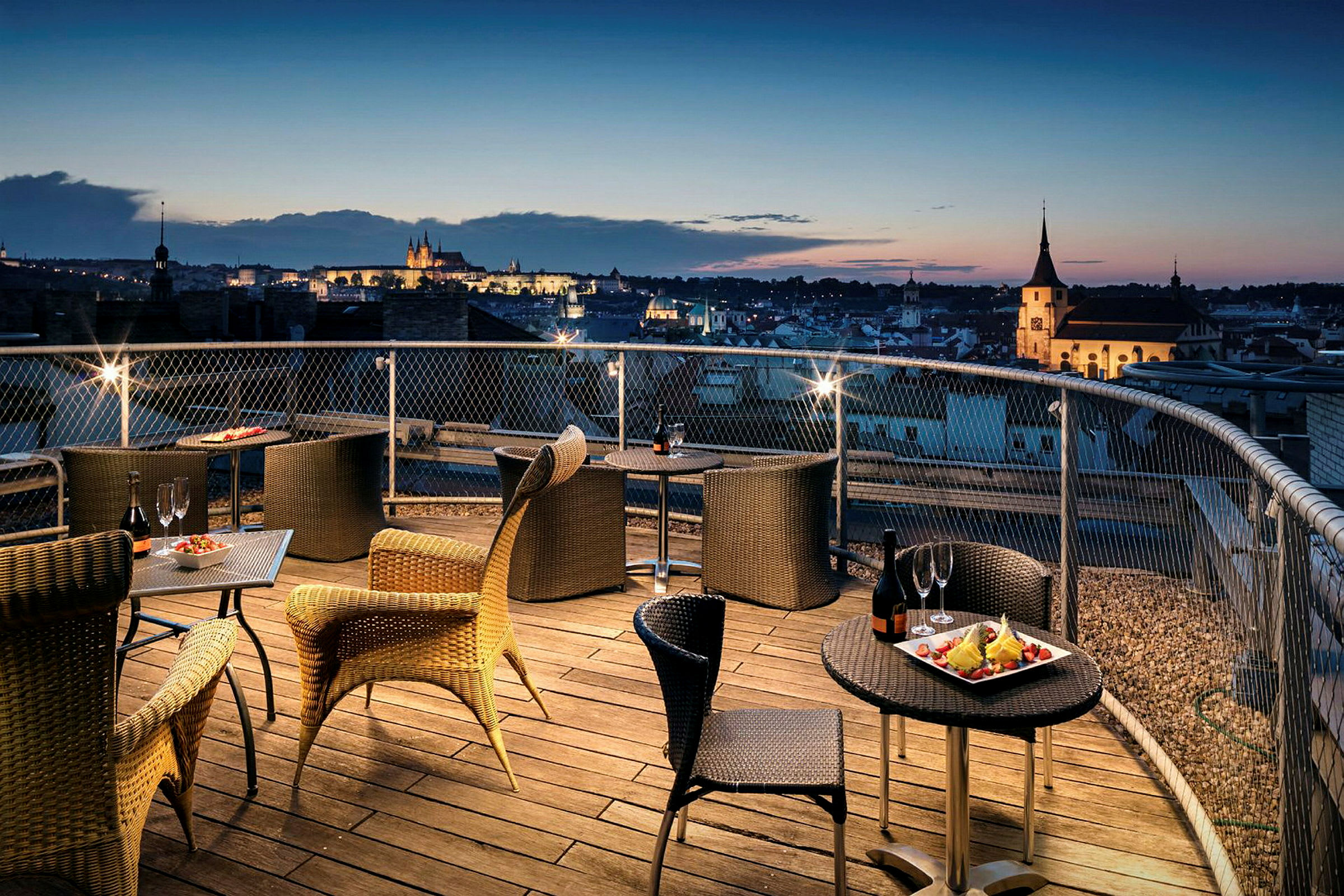 Terrass med sittplatser och utsikt över stad vid solnedgång. (AI-genererad text)