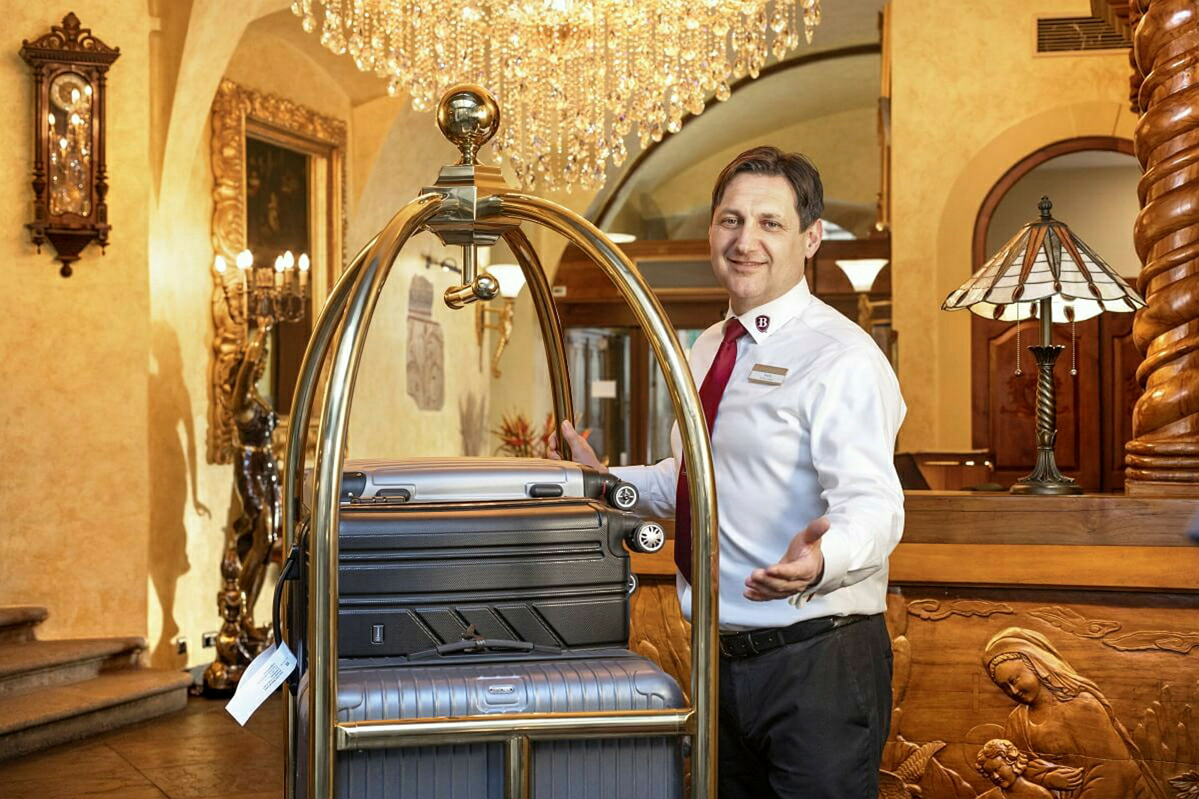 En hotellanställd vid en reception med resväskor på en bagagevagn. (AI-genererad text)